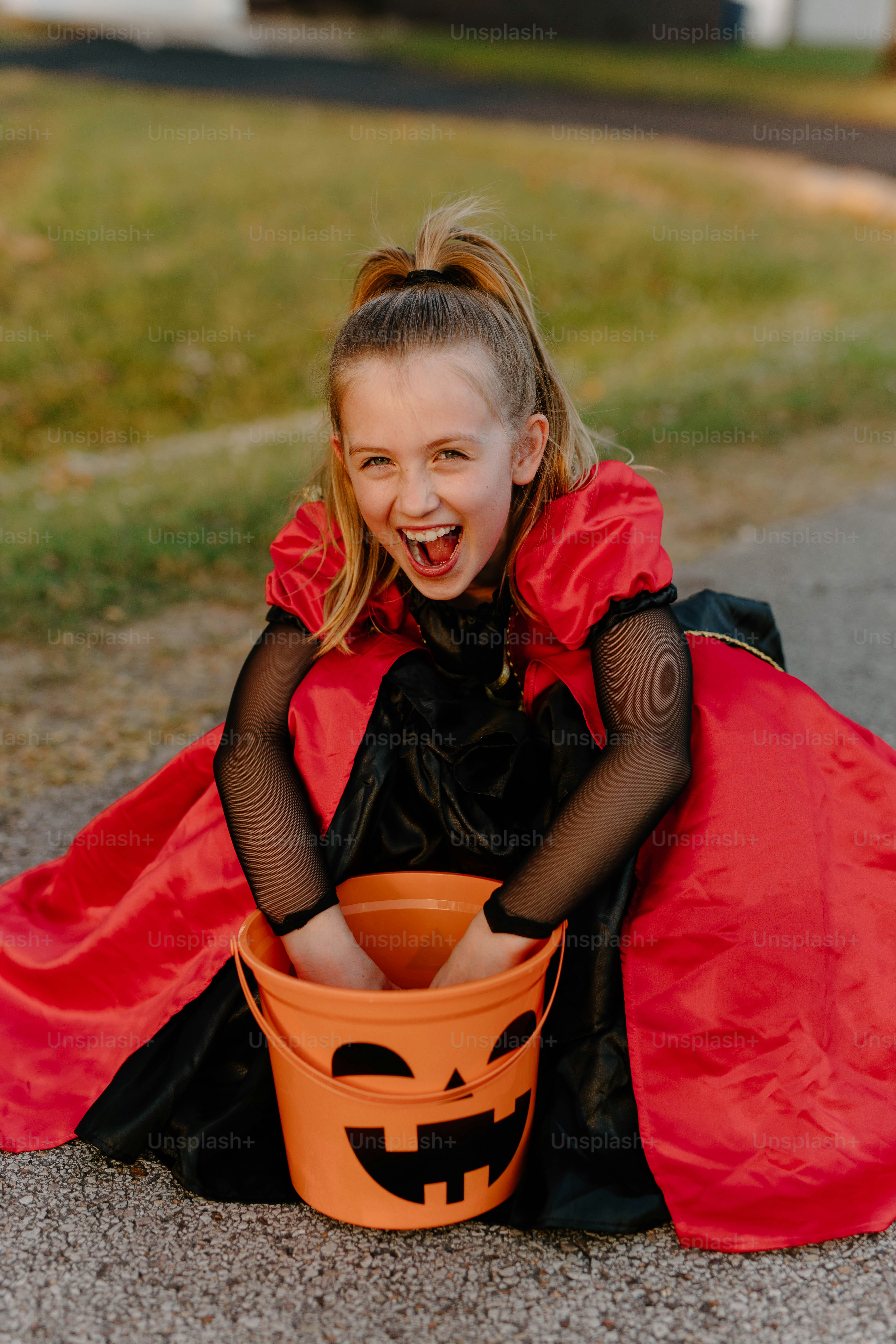Excited girl in costume with halloween candy bucket