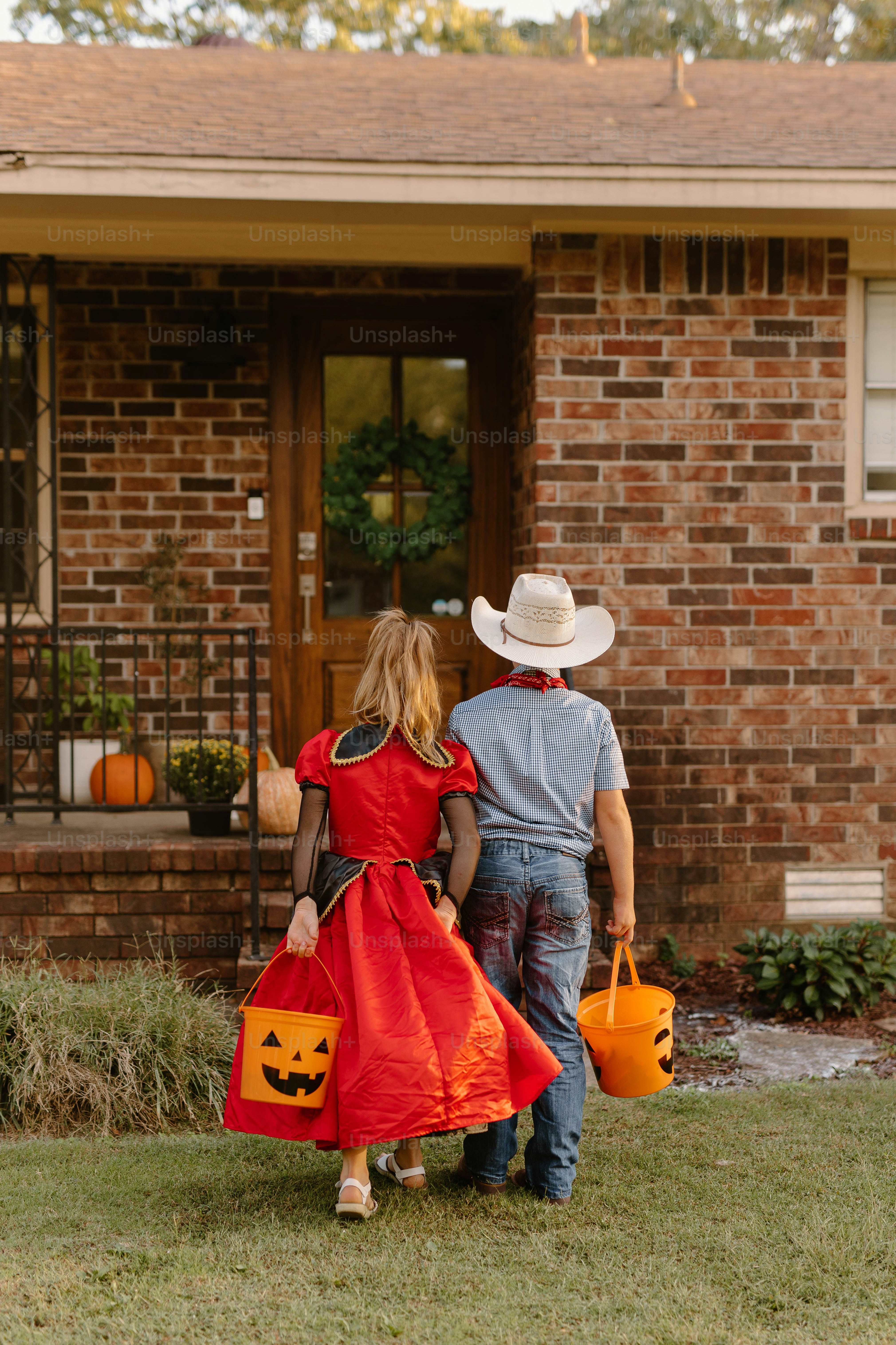Children in costumes trick-or-treating at a house.