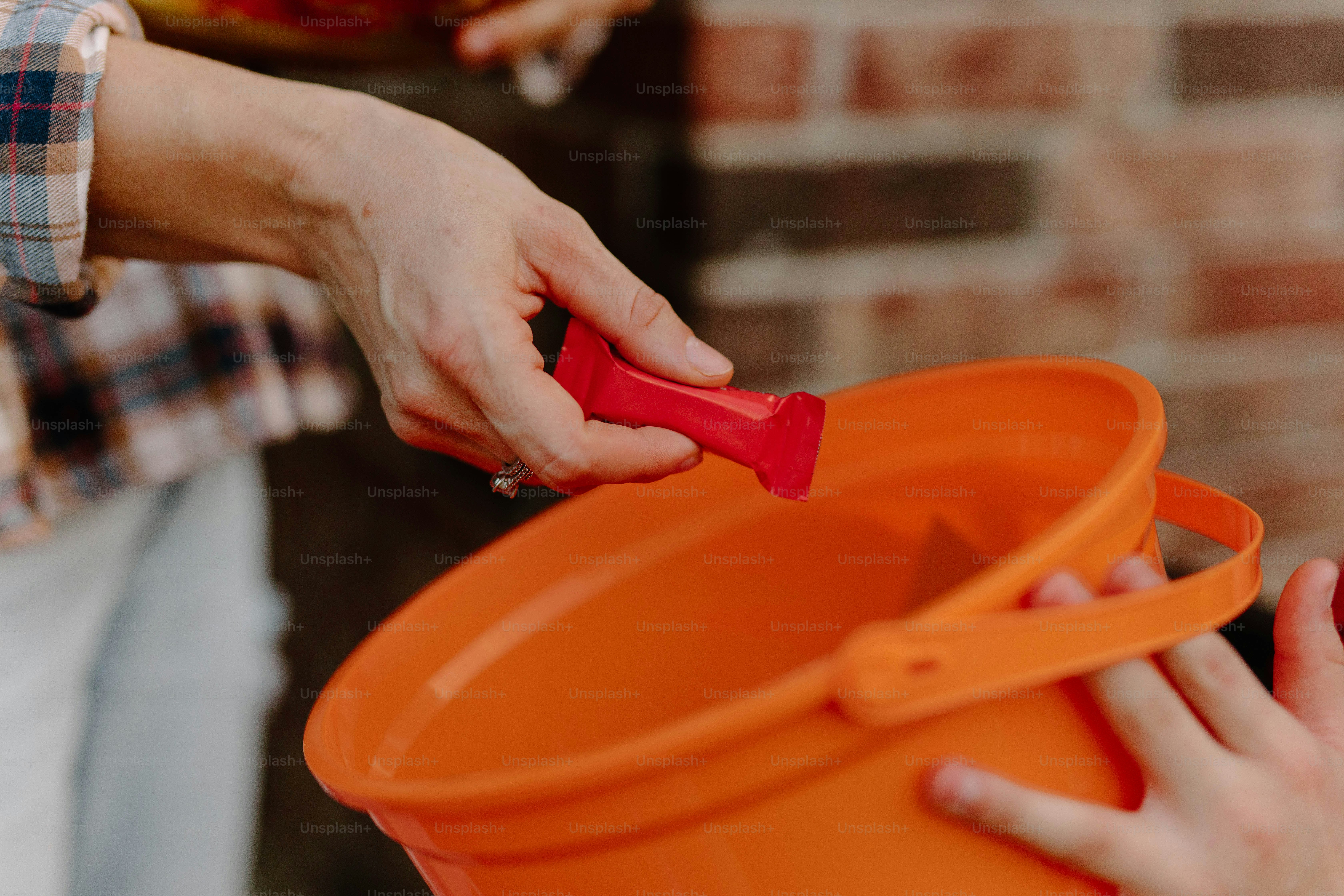 Hands giving candy into an orange bucket