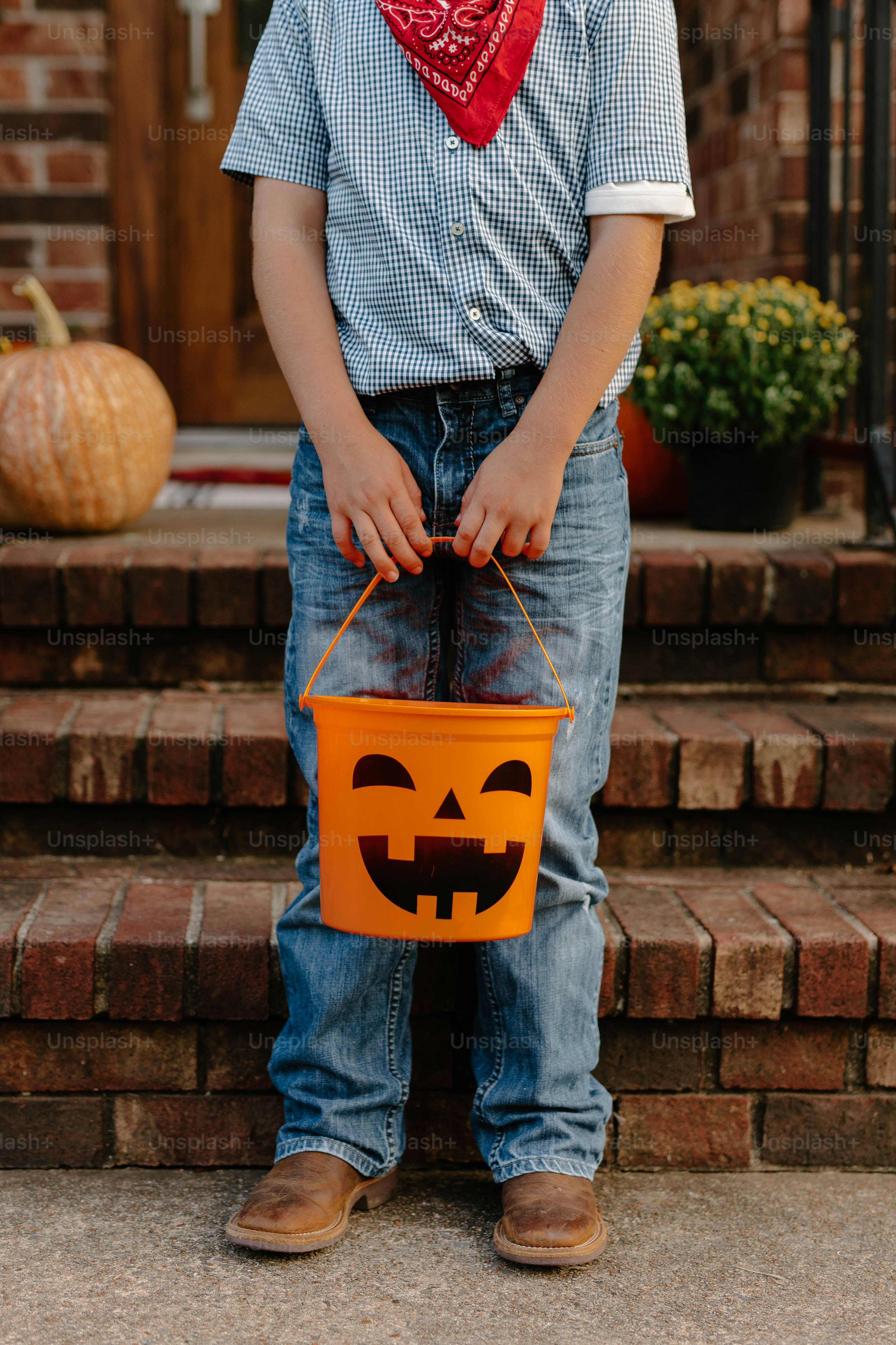 Child in costume holding a halloween pumpkin bucket.