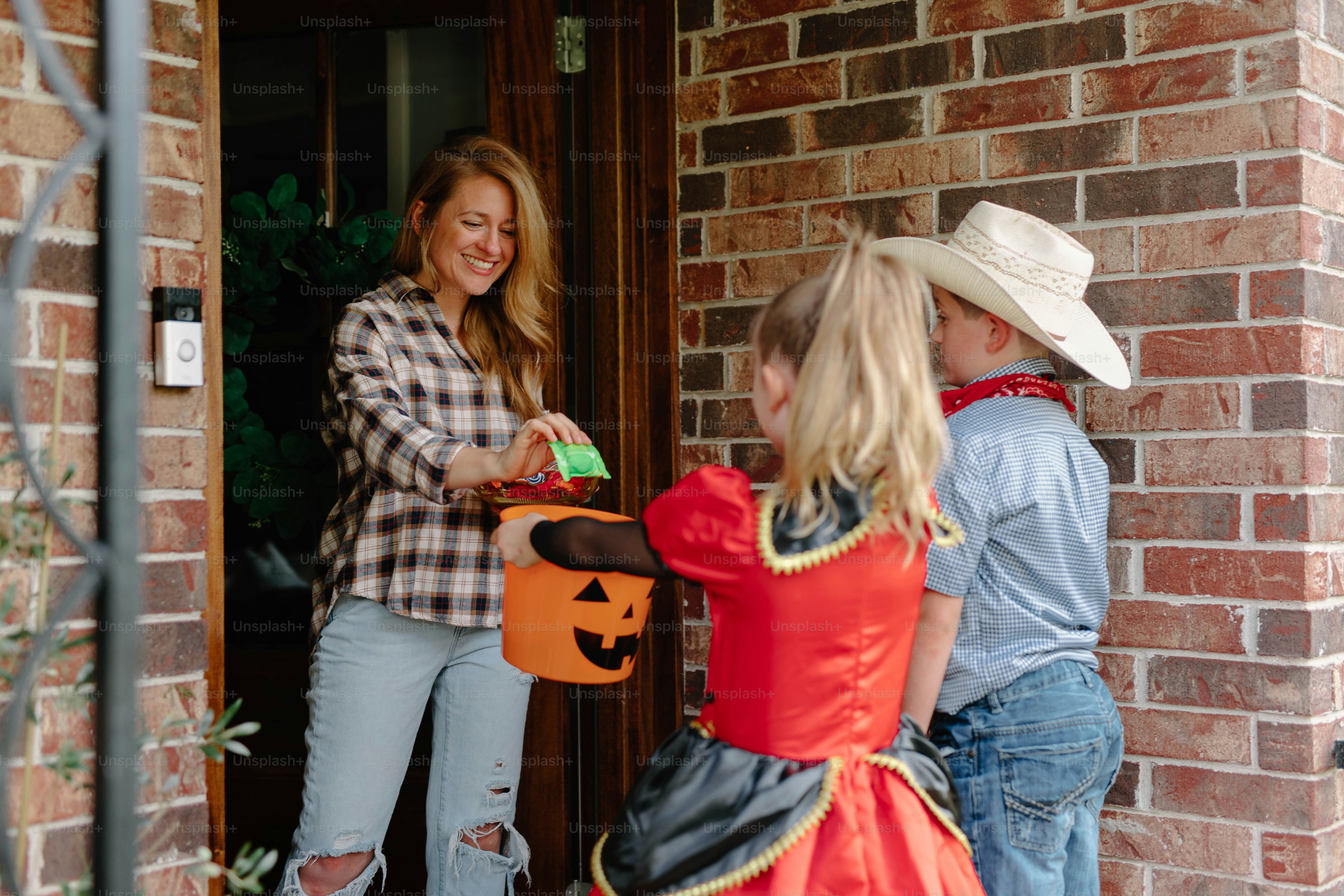 Woman giving candy to children in costumes