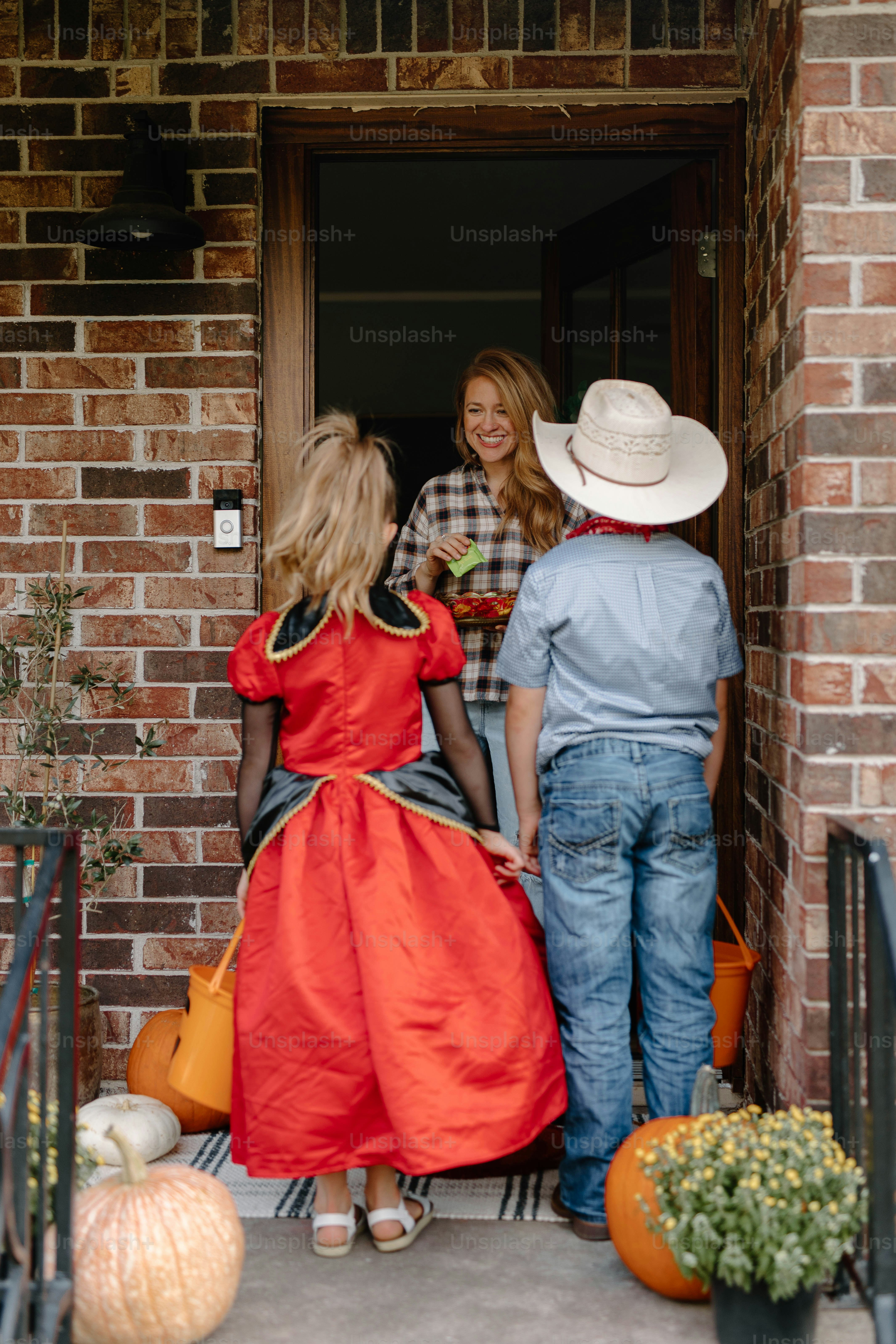 Mother greets children in halloween costumes at door