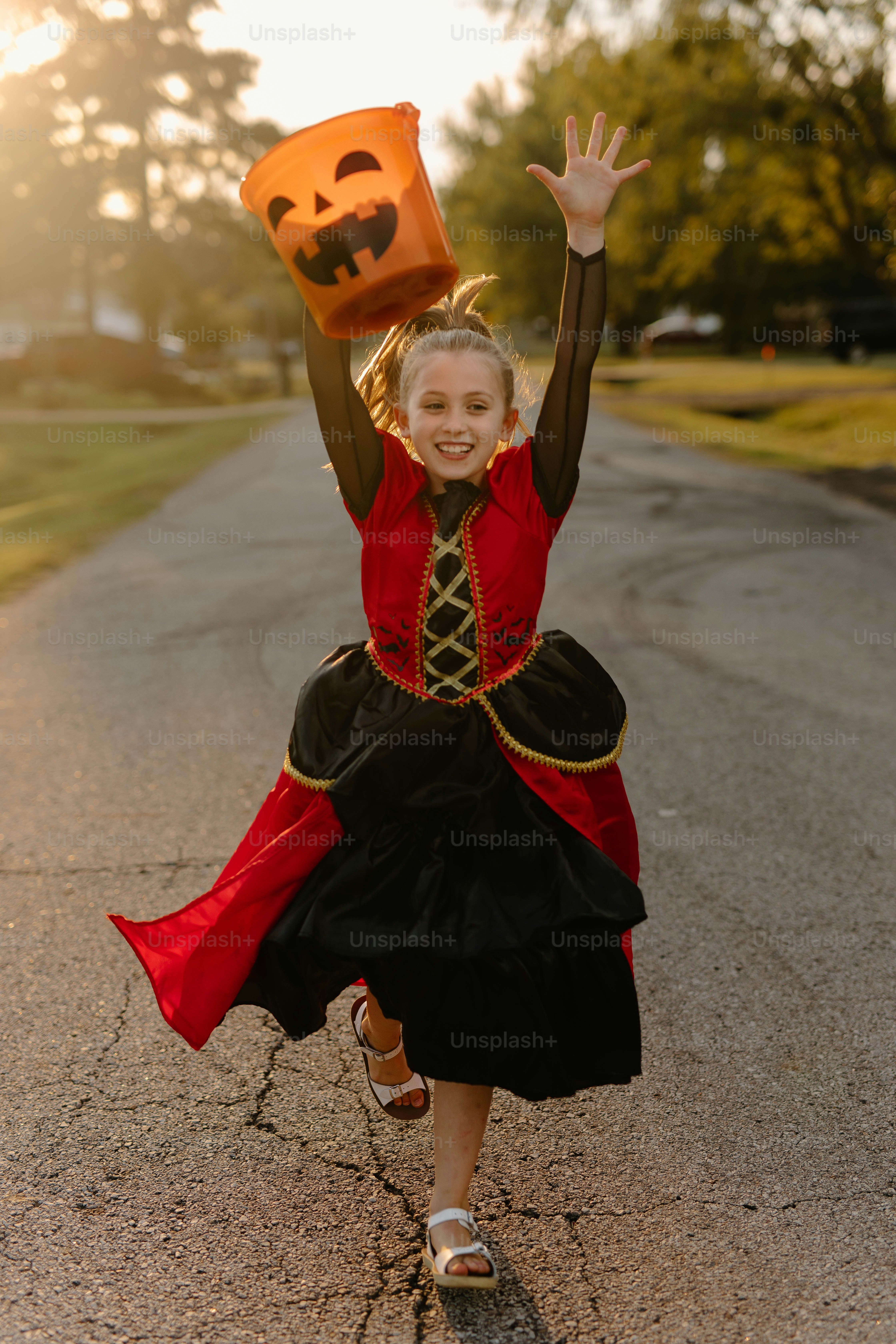 Girl in costume running with halloween bucket
