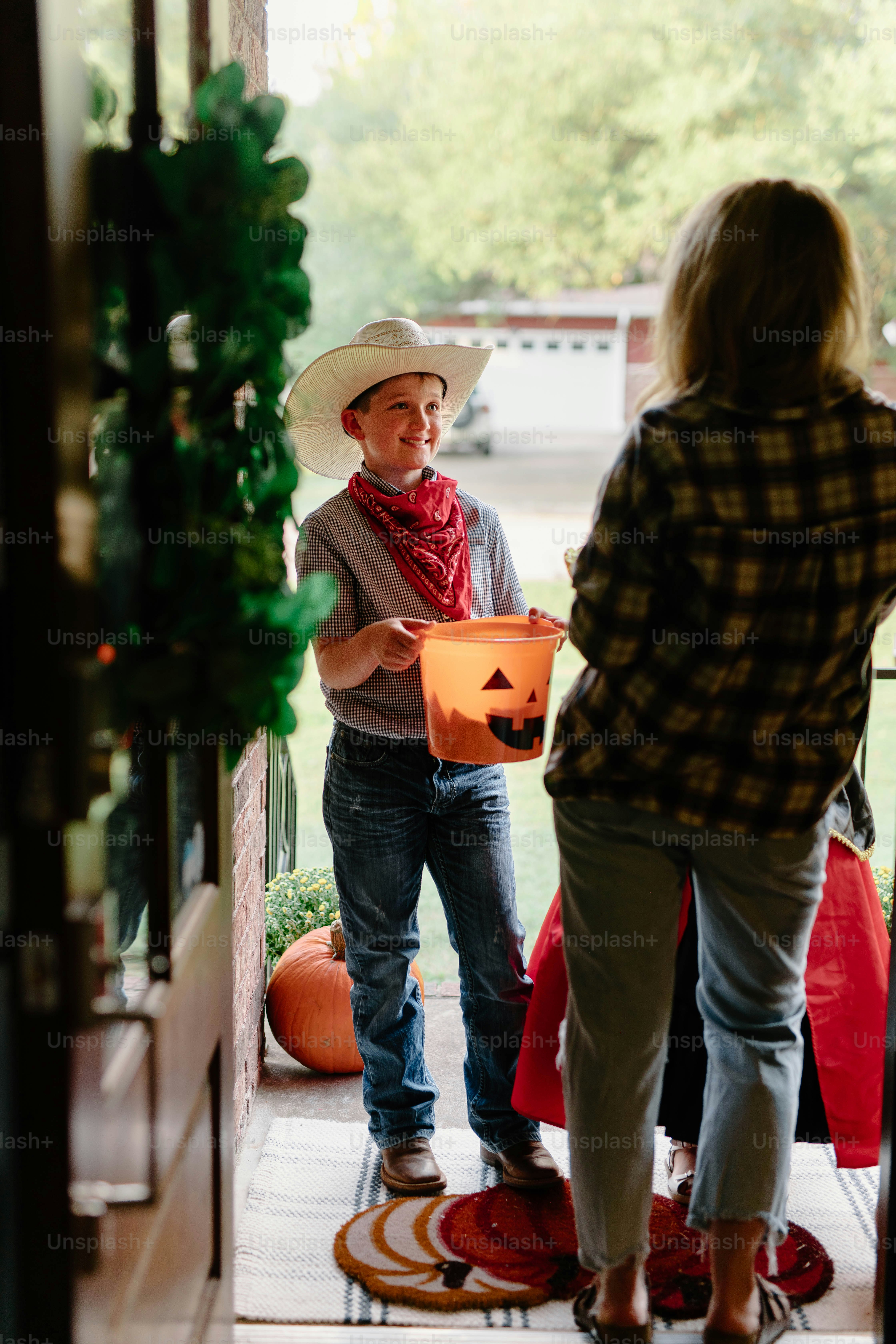 Boy in cowboy costume trick-or-treating at door