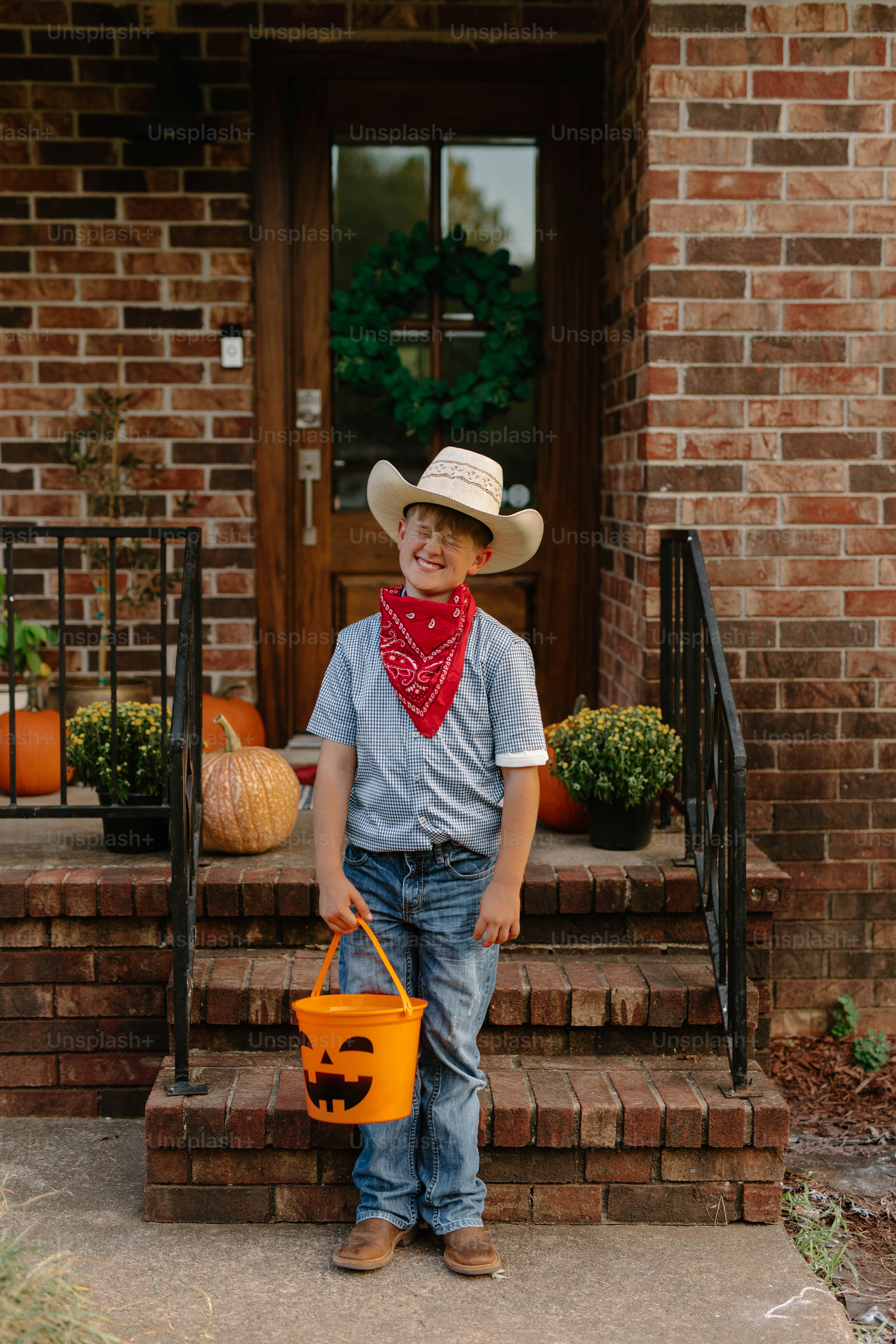 Boy in cowboy costume holding pumpkin bucket