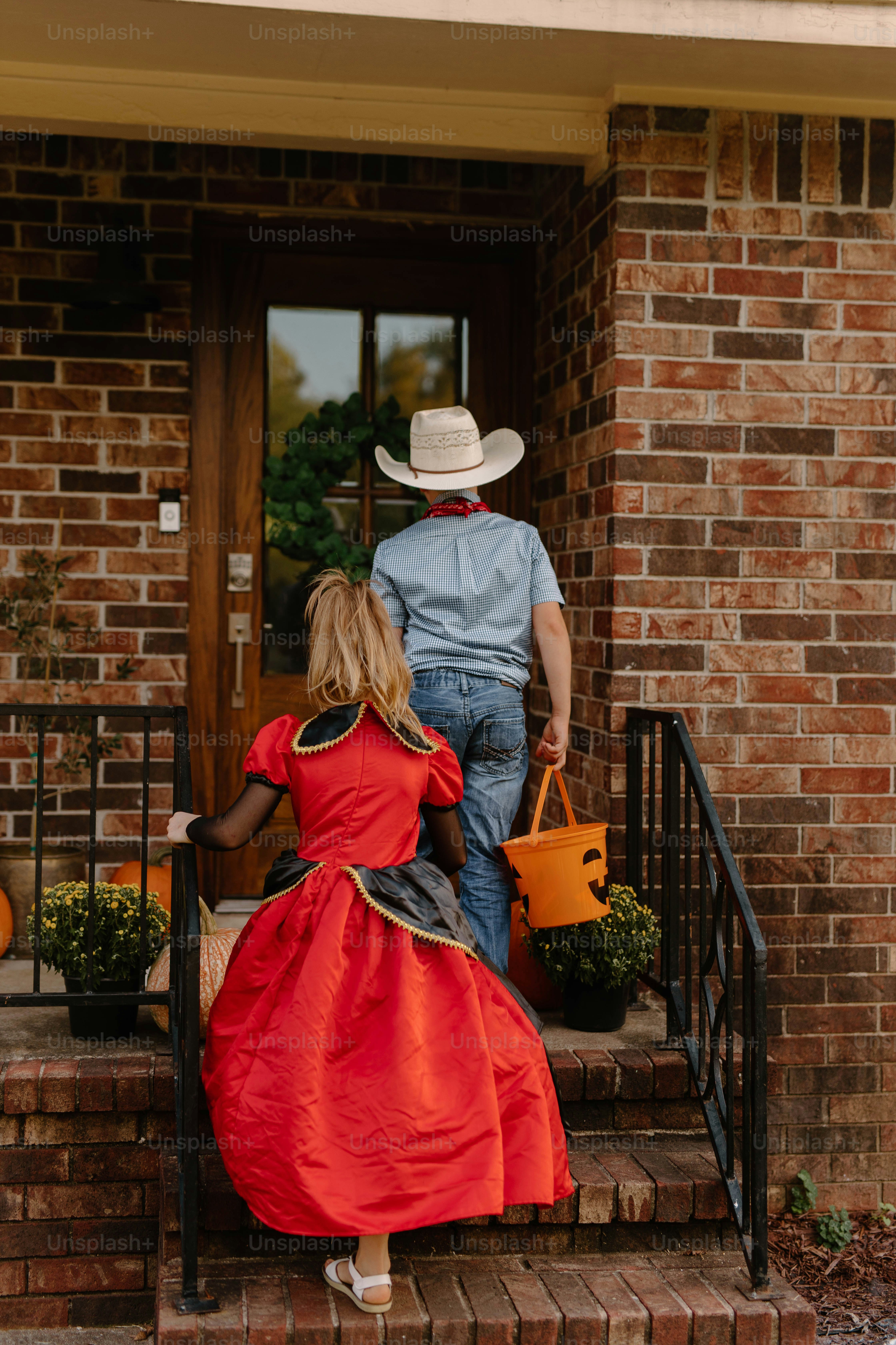 Children in costumes walk up steps to a door.