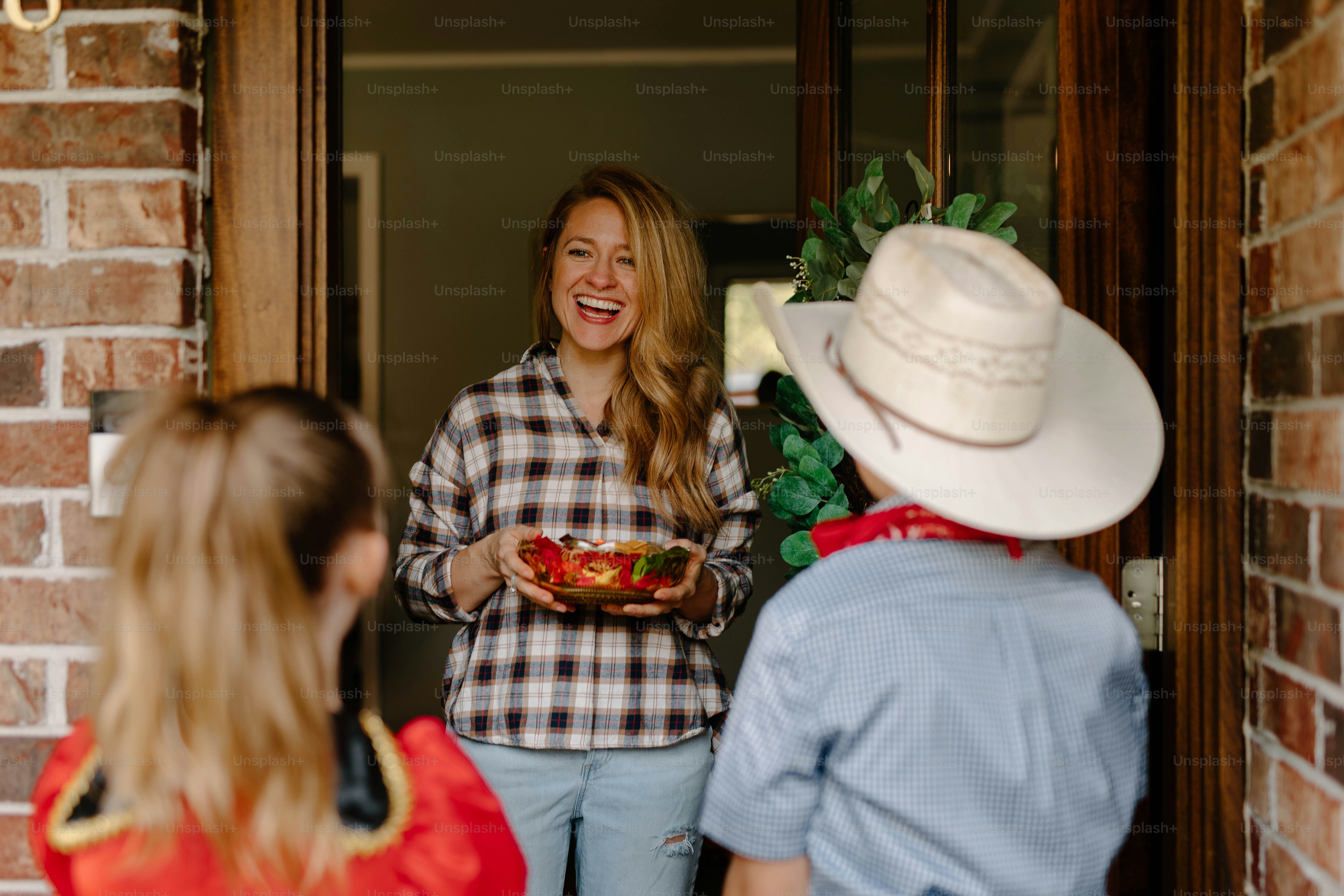 Woman greets children at the door with candy