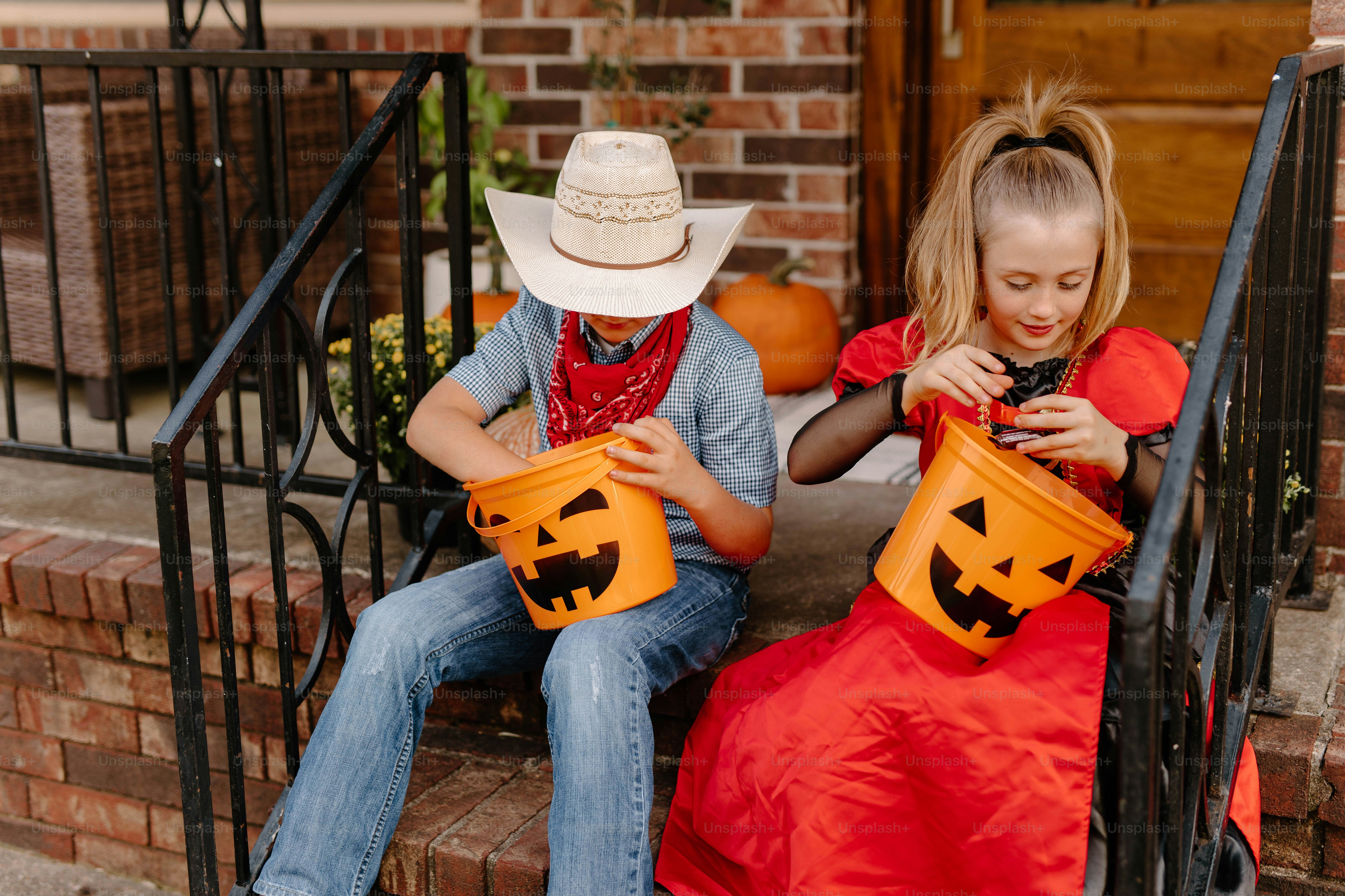 Two children in costumes with halloween candy buckets