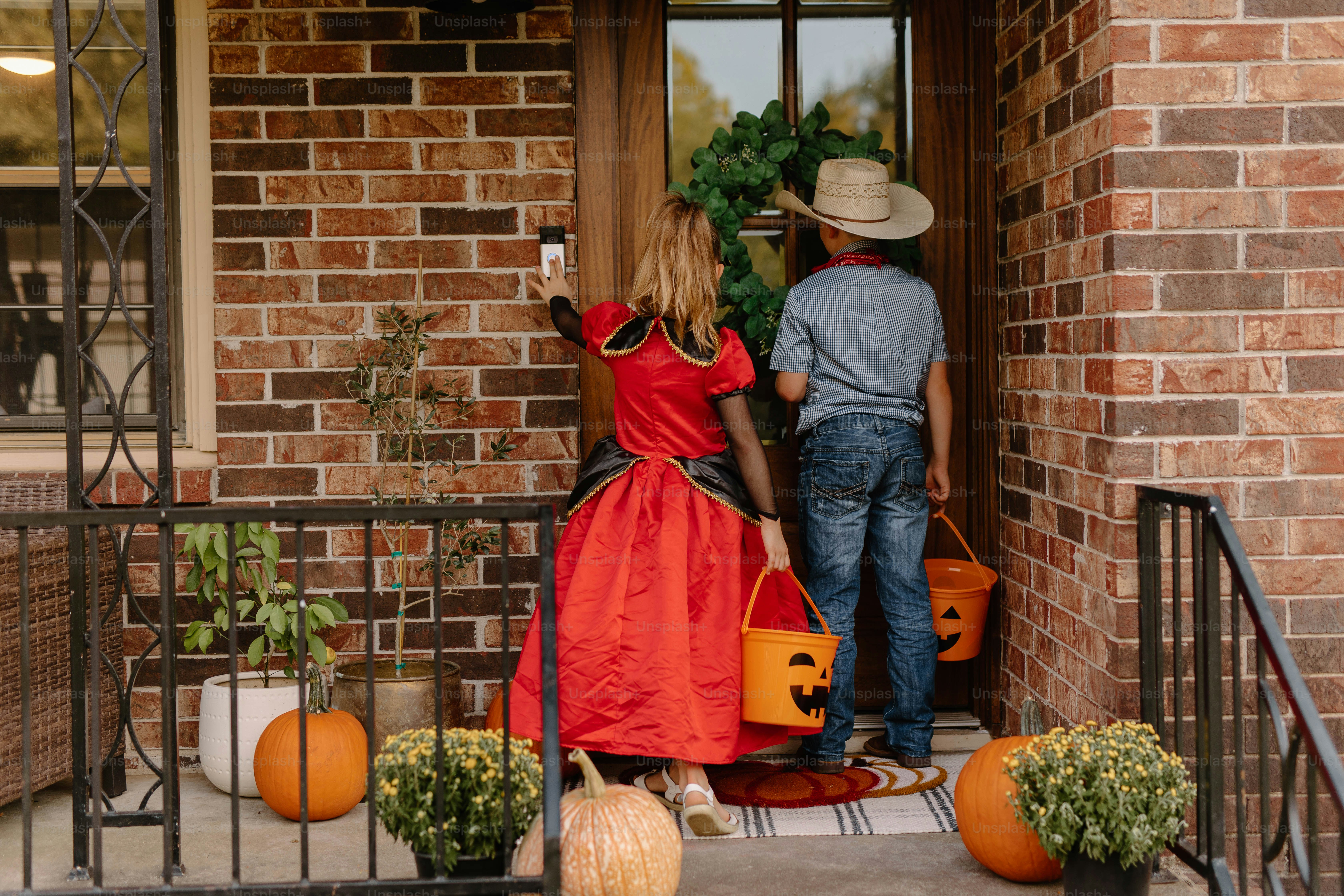 Children in costumes ring doorbell with candy buckets