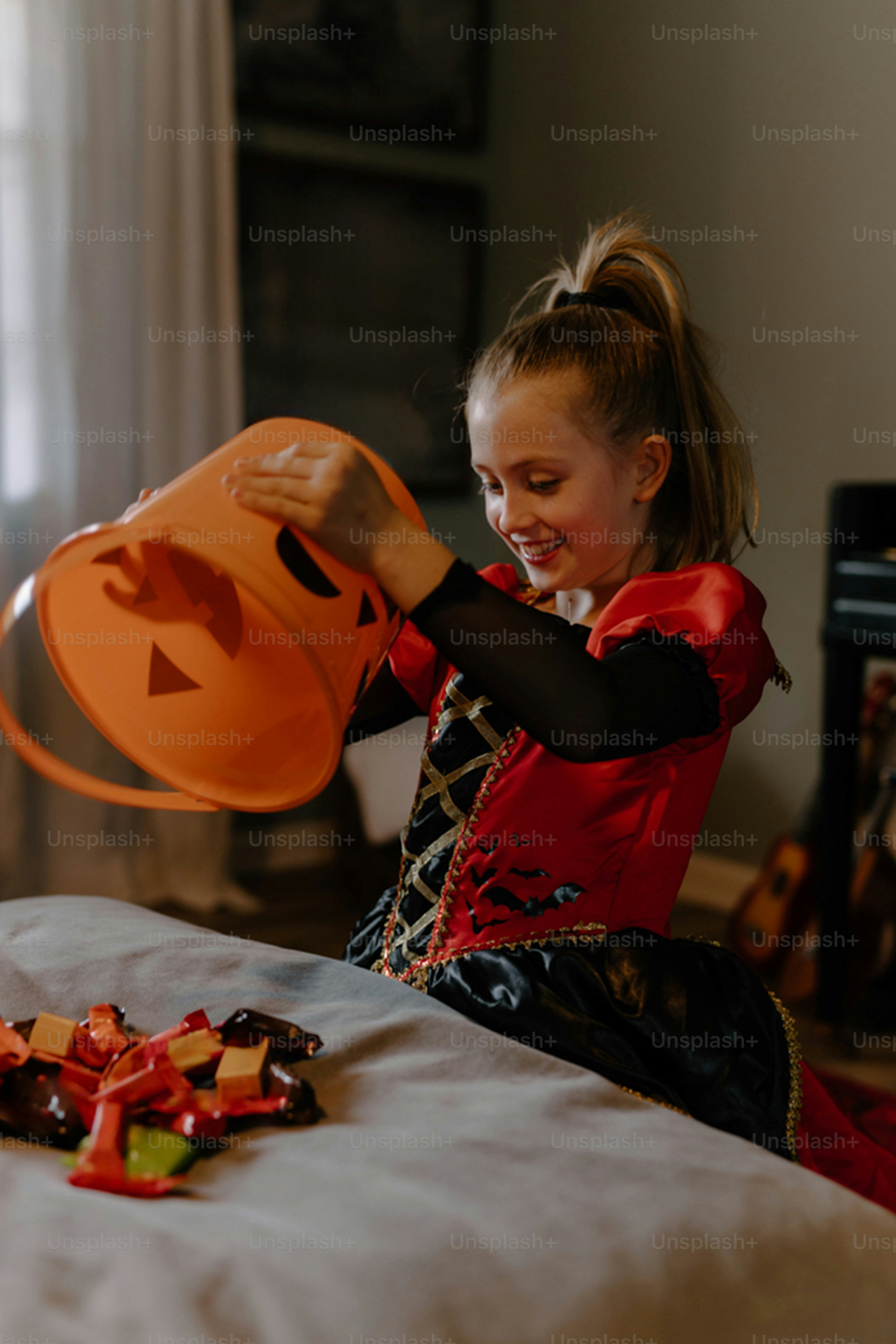 Girl in costume looks into halloween candy bucket