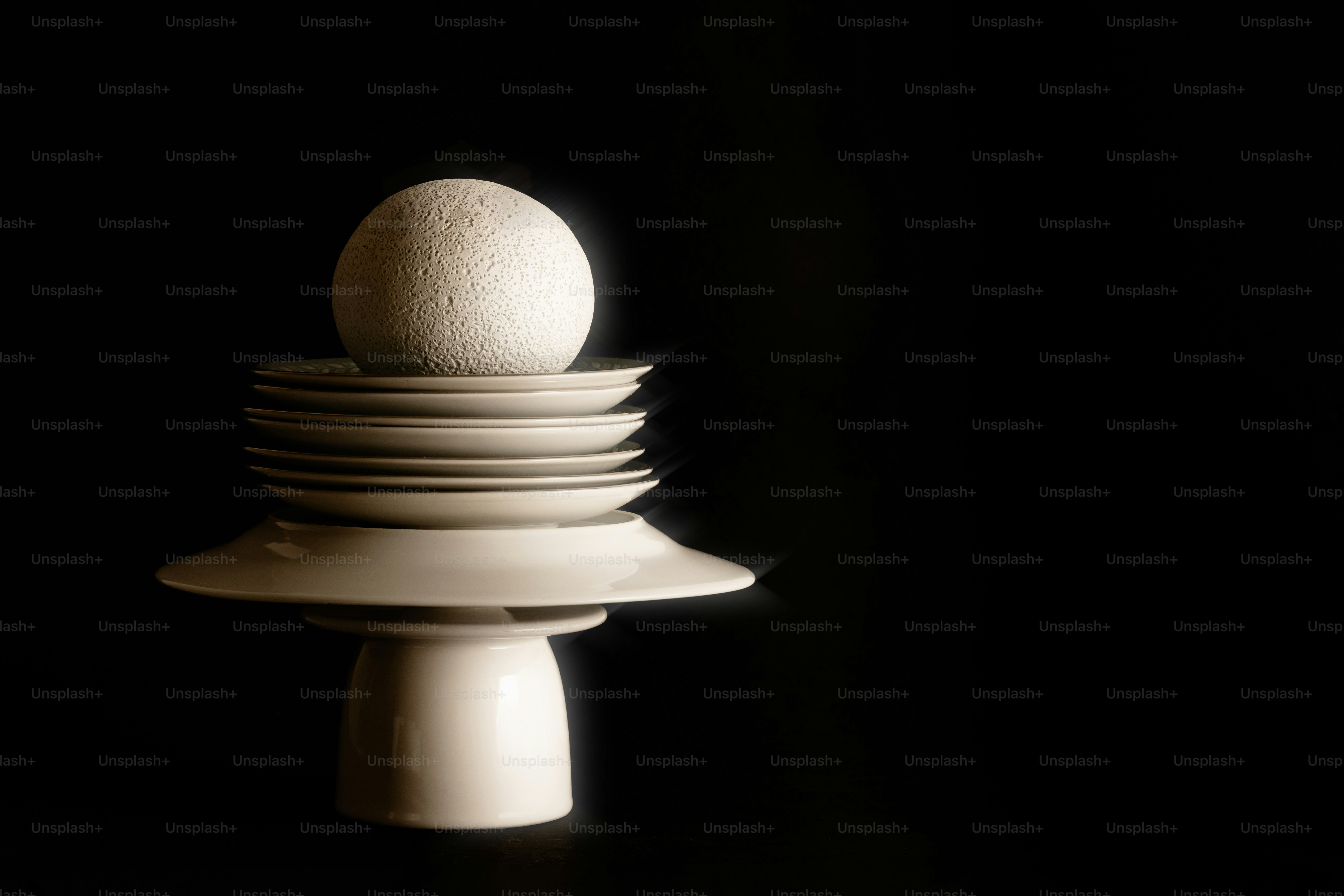 Piatti impilati sormontati da una sfera contro il nero