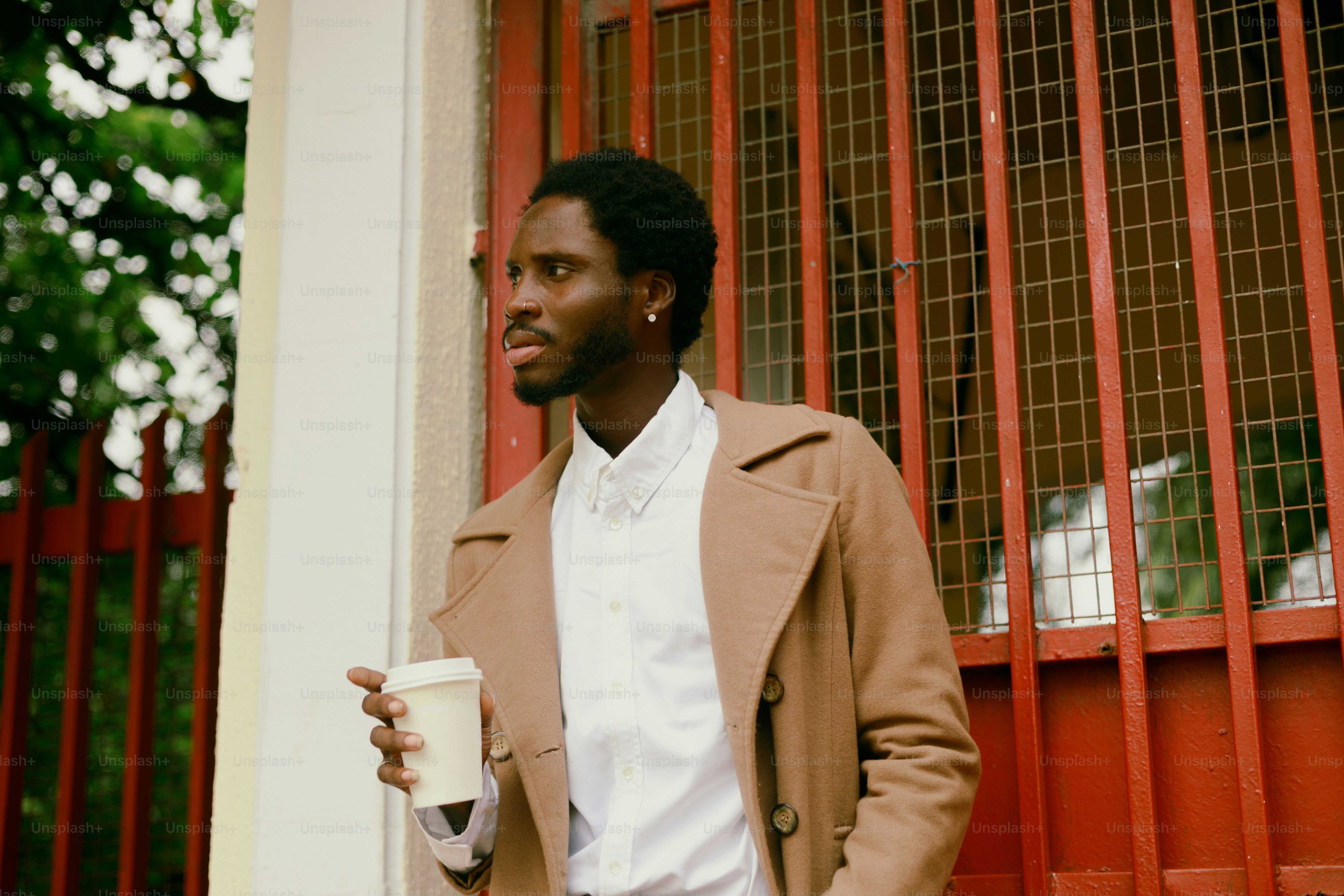 Man in coat holding coffee cup near red door