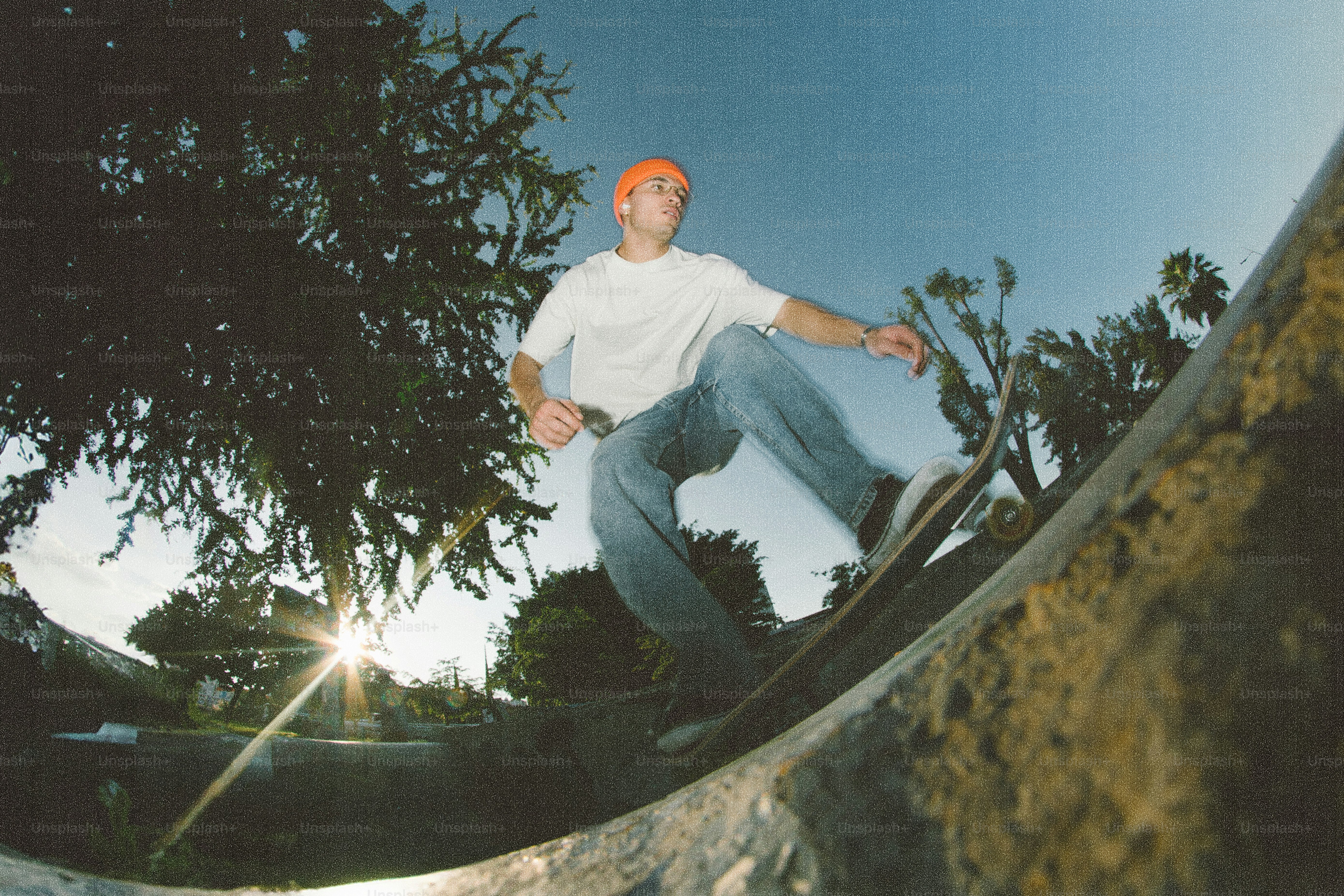 Lo skateboarder cavalca una rampa al tramonto