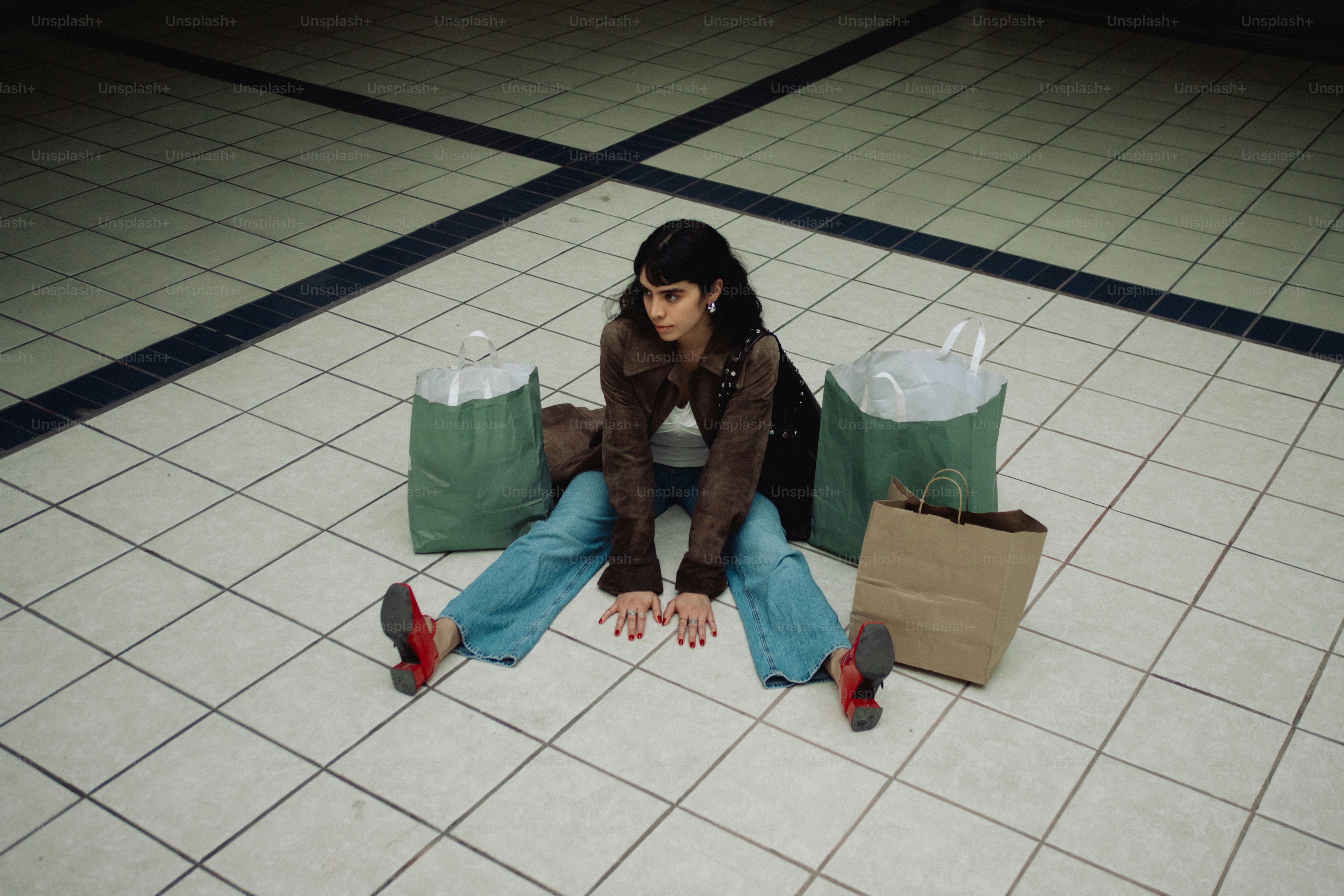 Woman sitting on tiled floor with shopping bags
