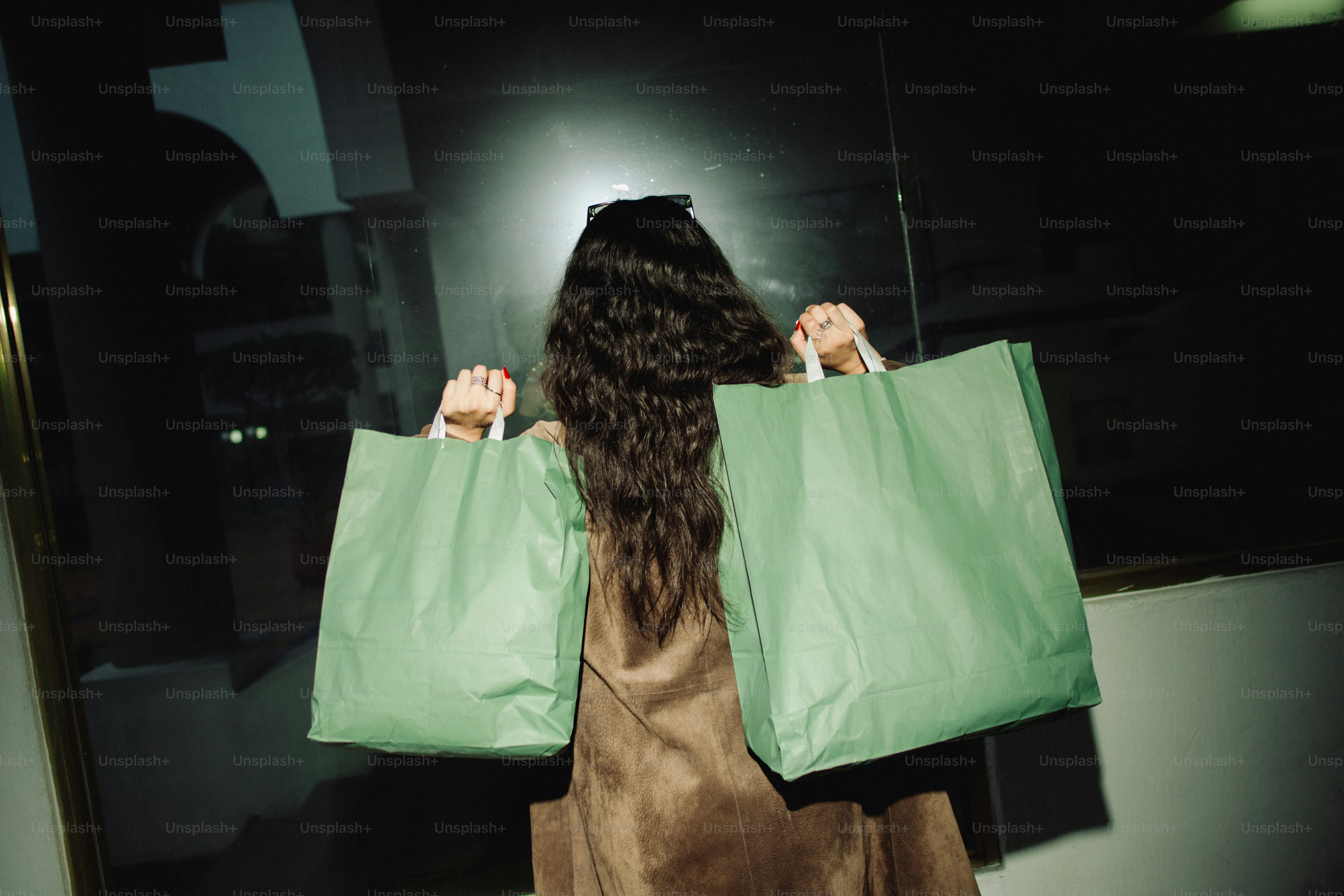 Woman holding two green shopping bags.