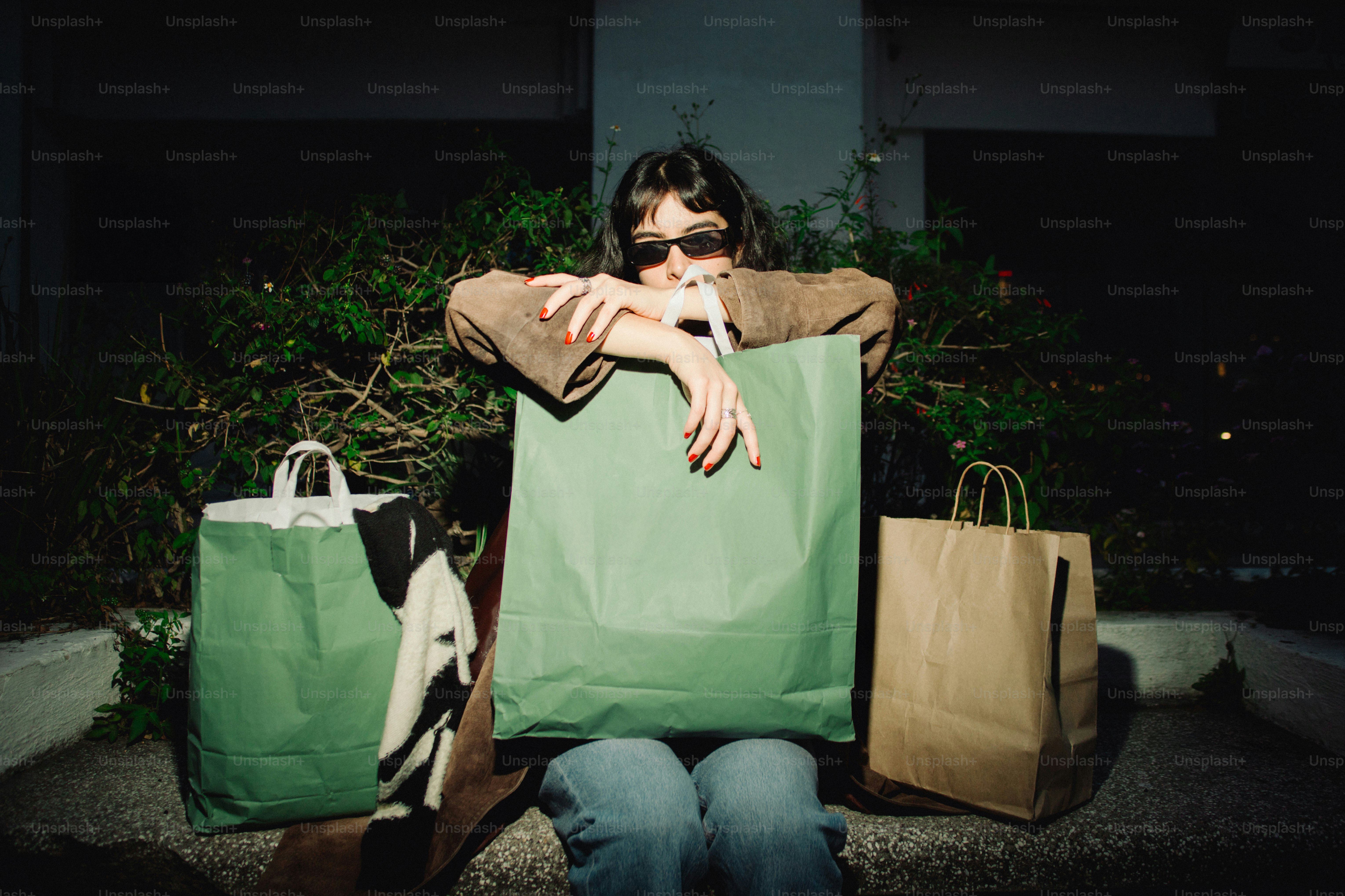 Woman with shopping bags sits outdoors at night.
