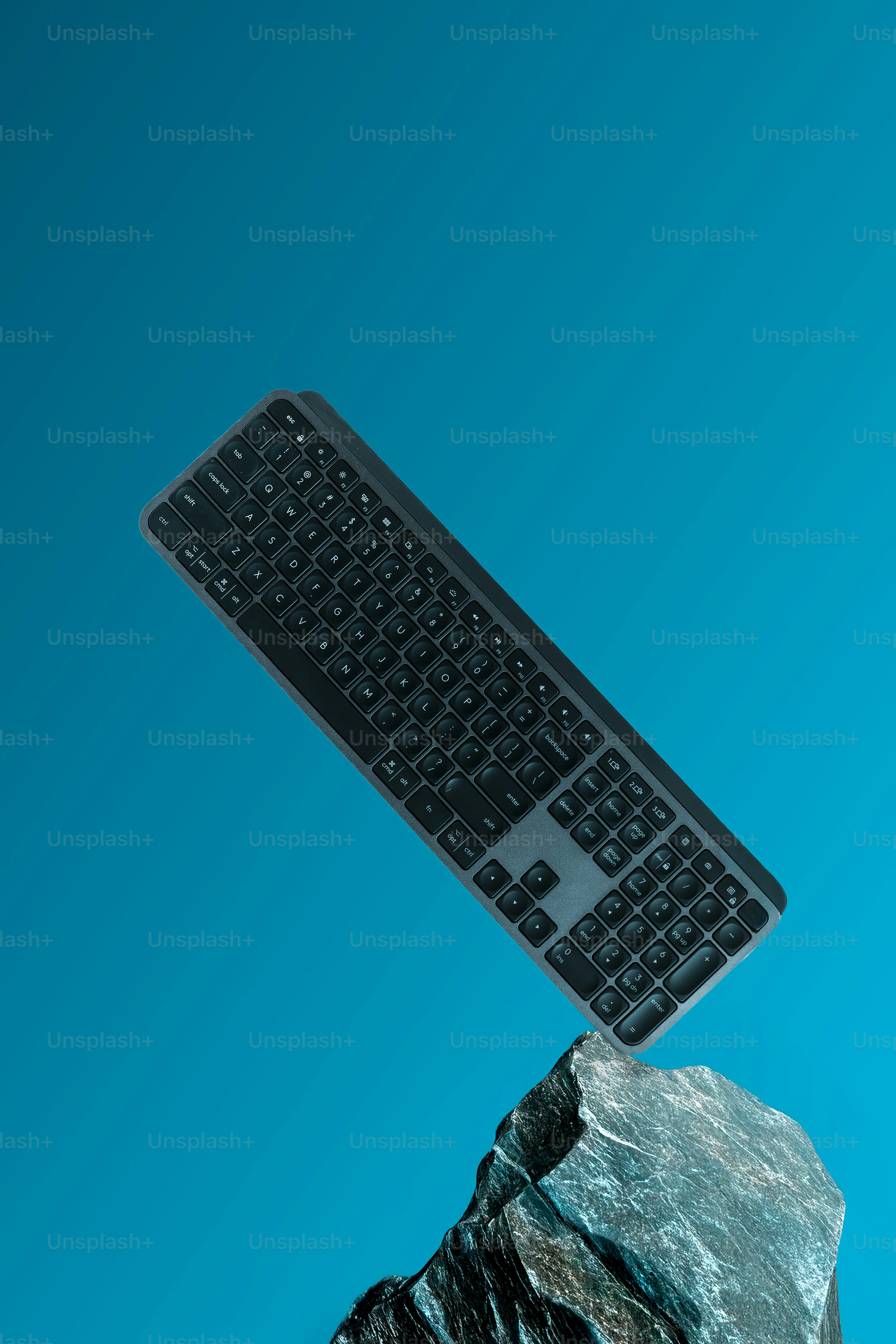 A black keyboard balanced on a rock.