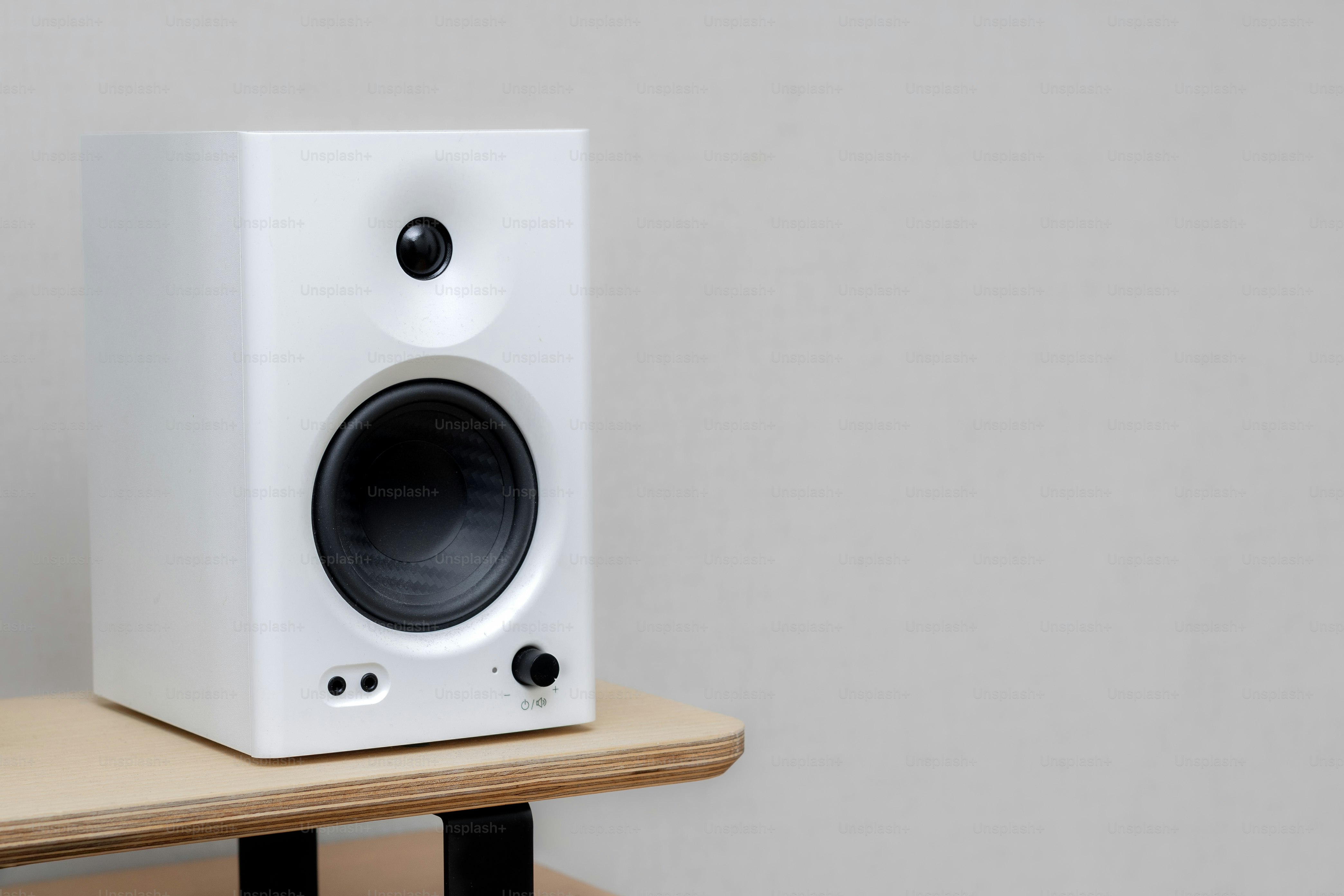 A white speaker sits on a wooden shelf.
