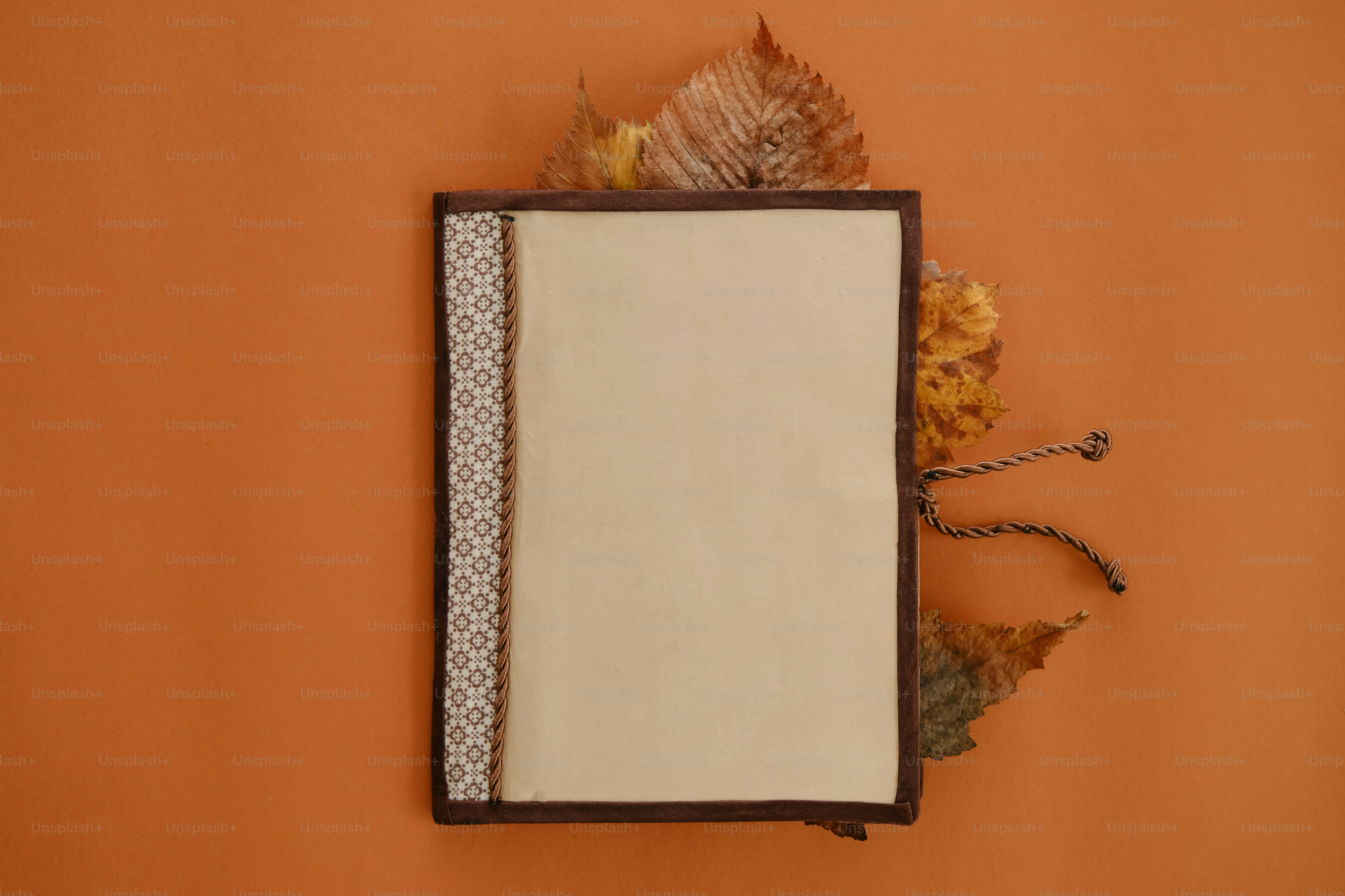 Blank notebook with autumn leaves on orange background