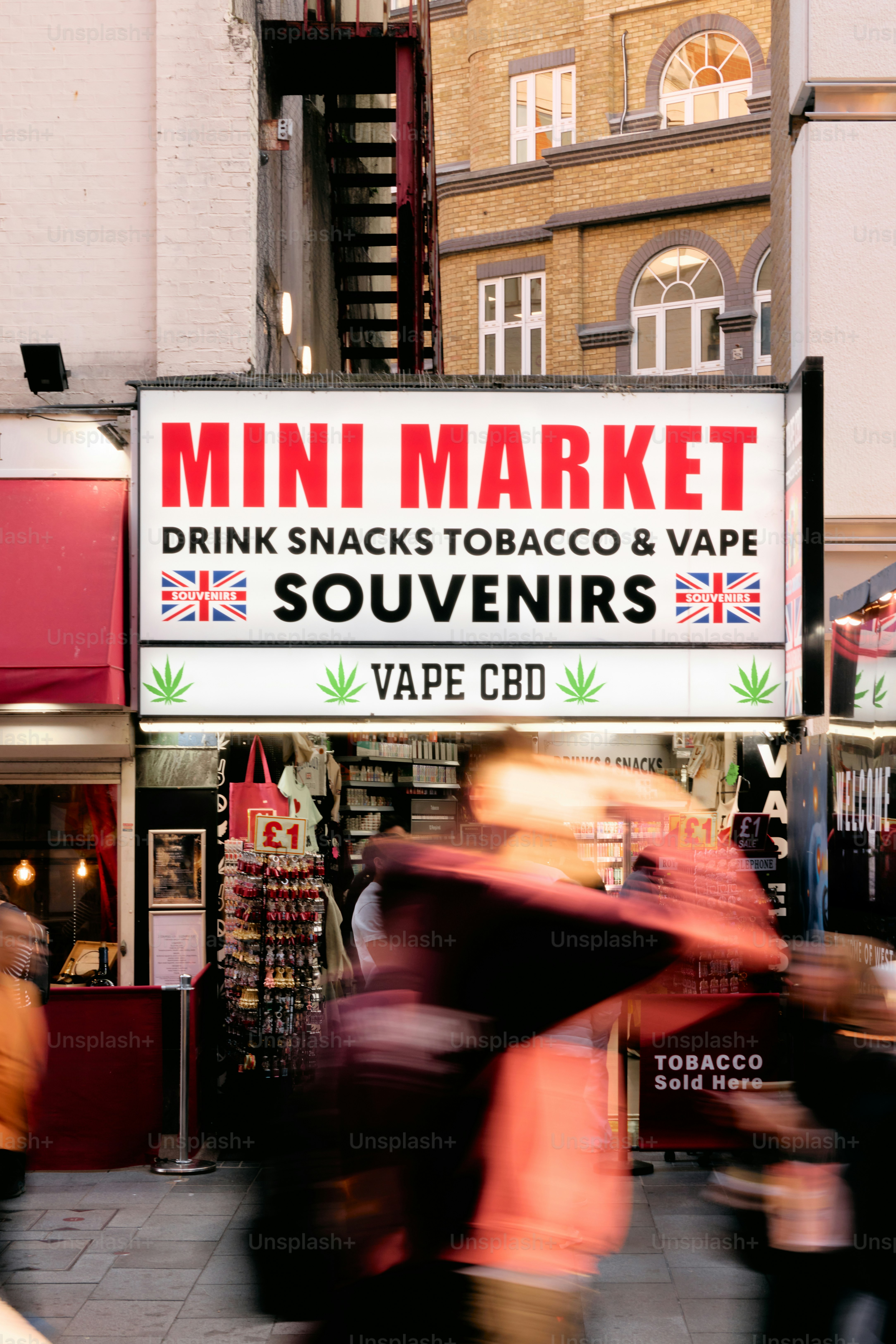 Mini market sign advertising drinks, snacks, tobacco, vape, and souvenirs.