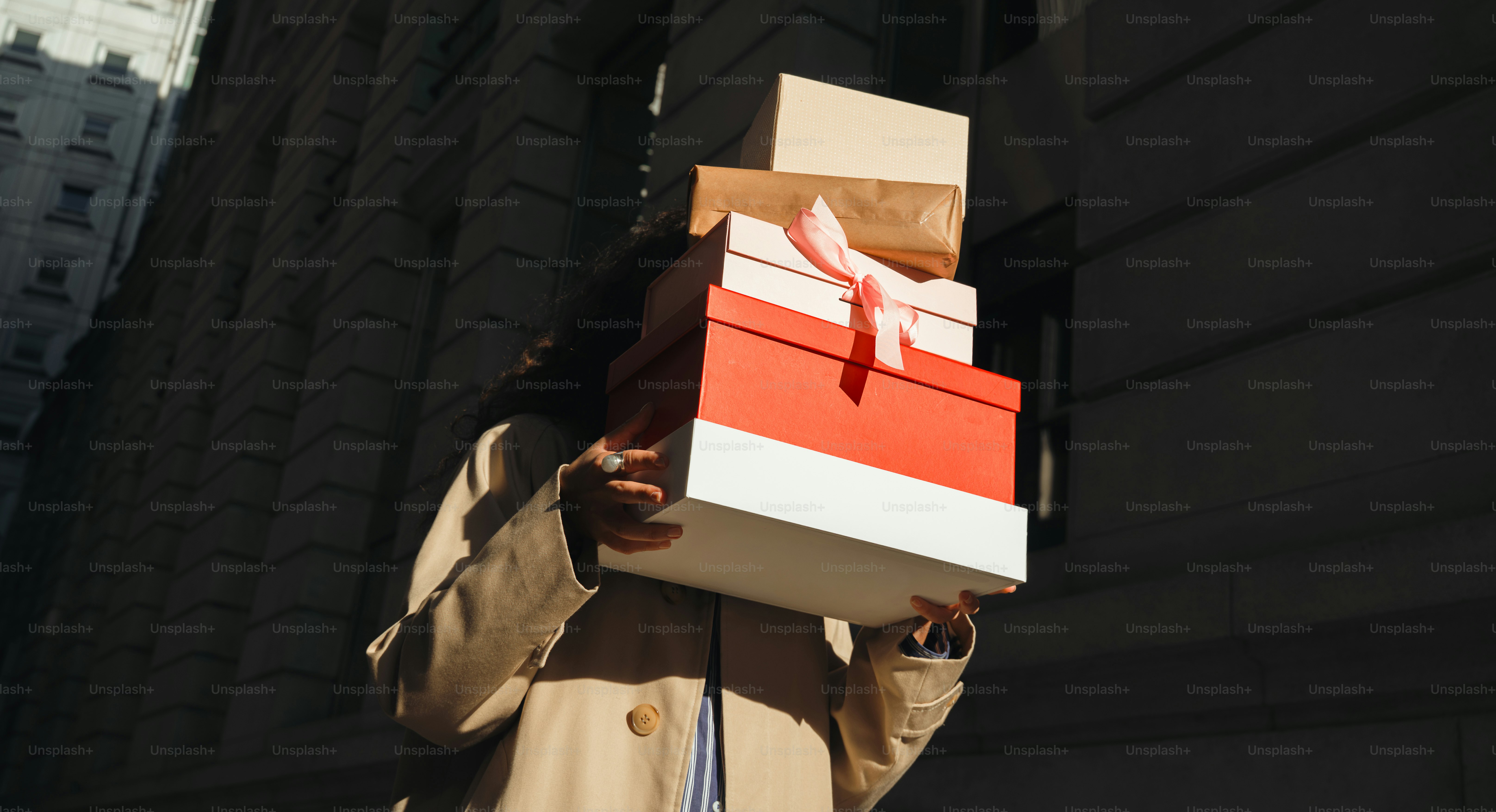Woman carrying stack of gift boxes on city street