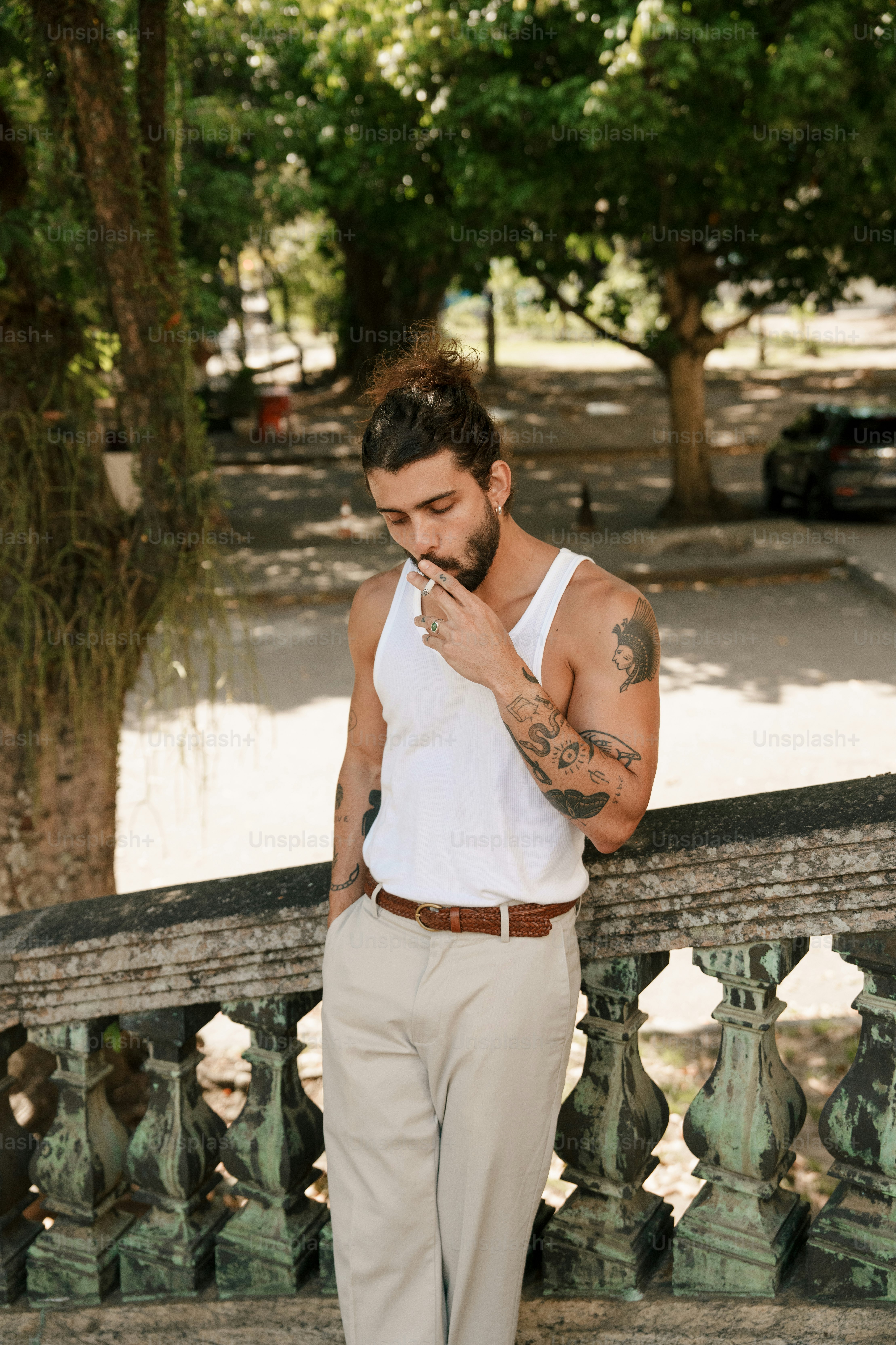 Mann im Tanktop raucht im Freien mit Tattoos