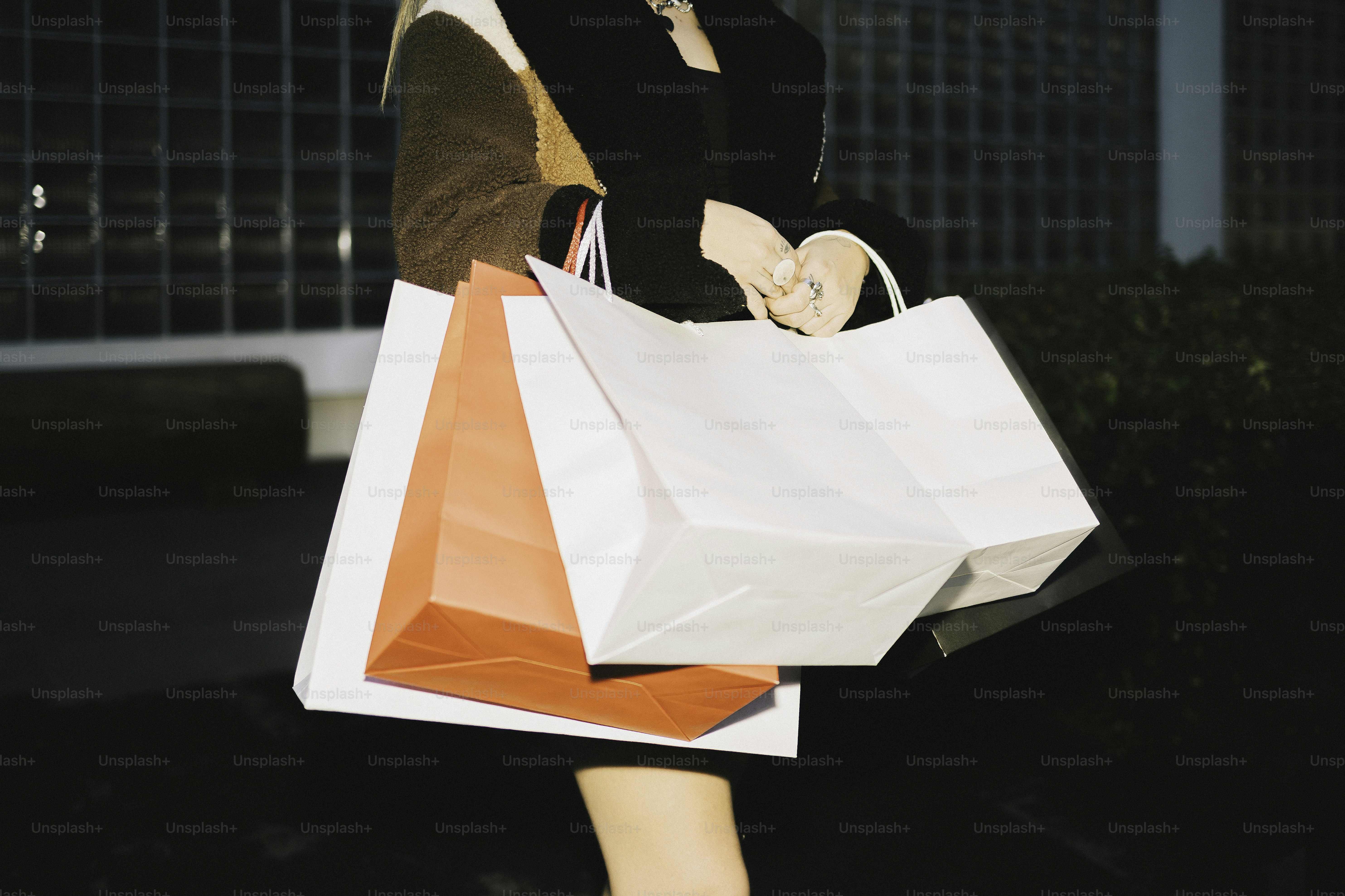 Woman holding shopping bags outdoors at dusk