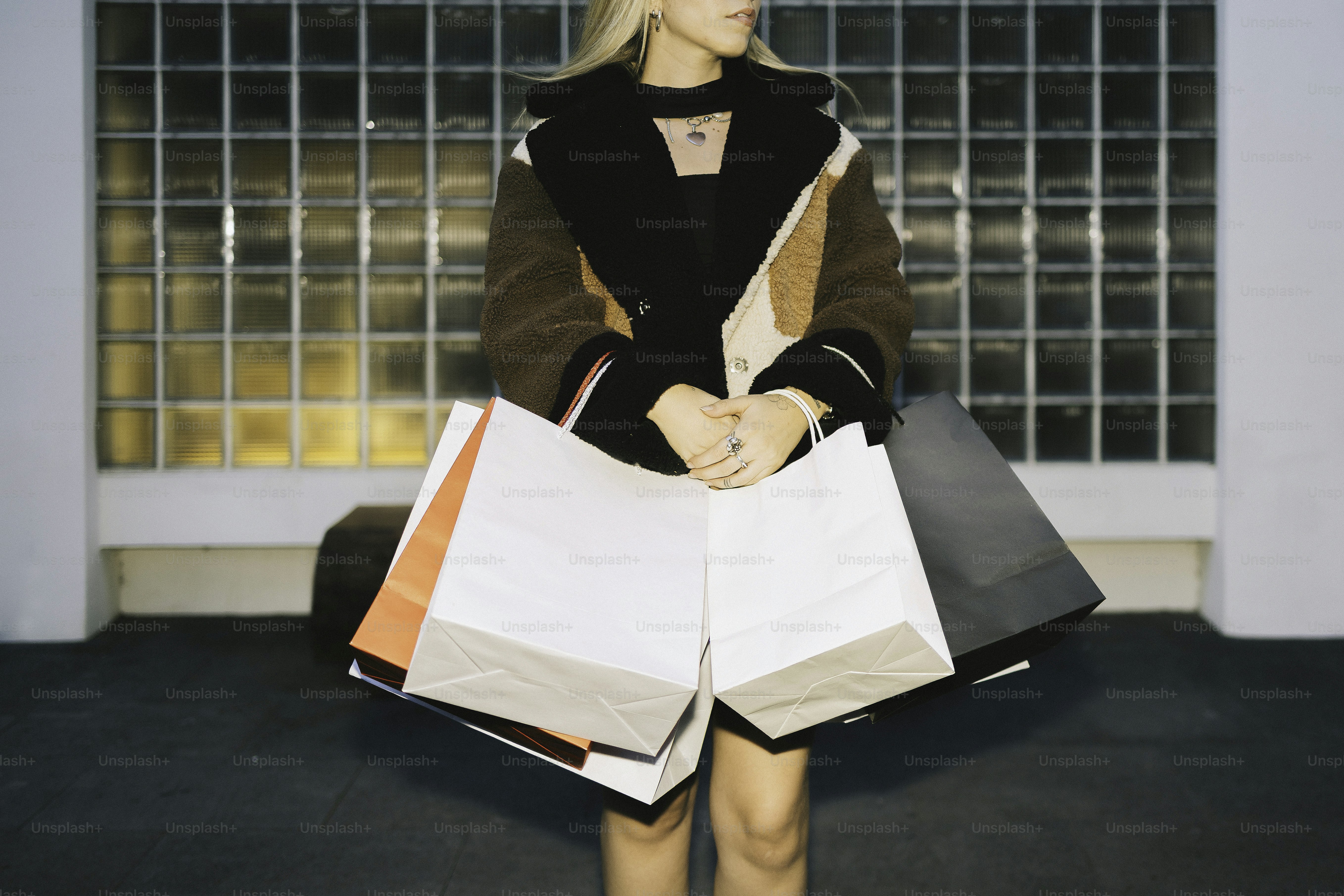 Woman holding shopping bags in front of glass wall