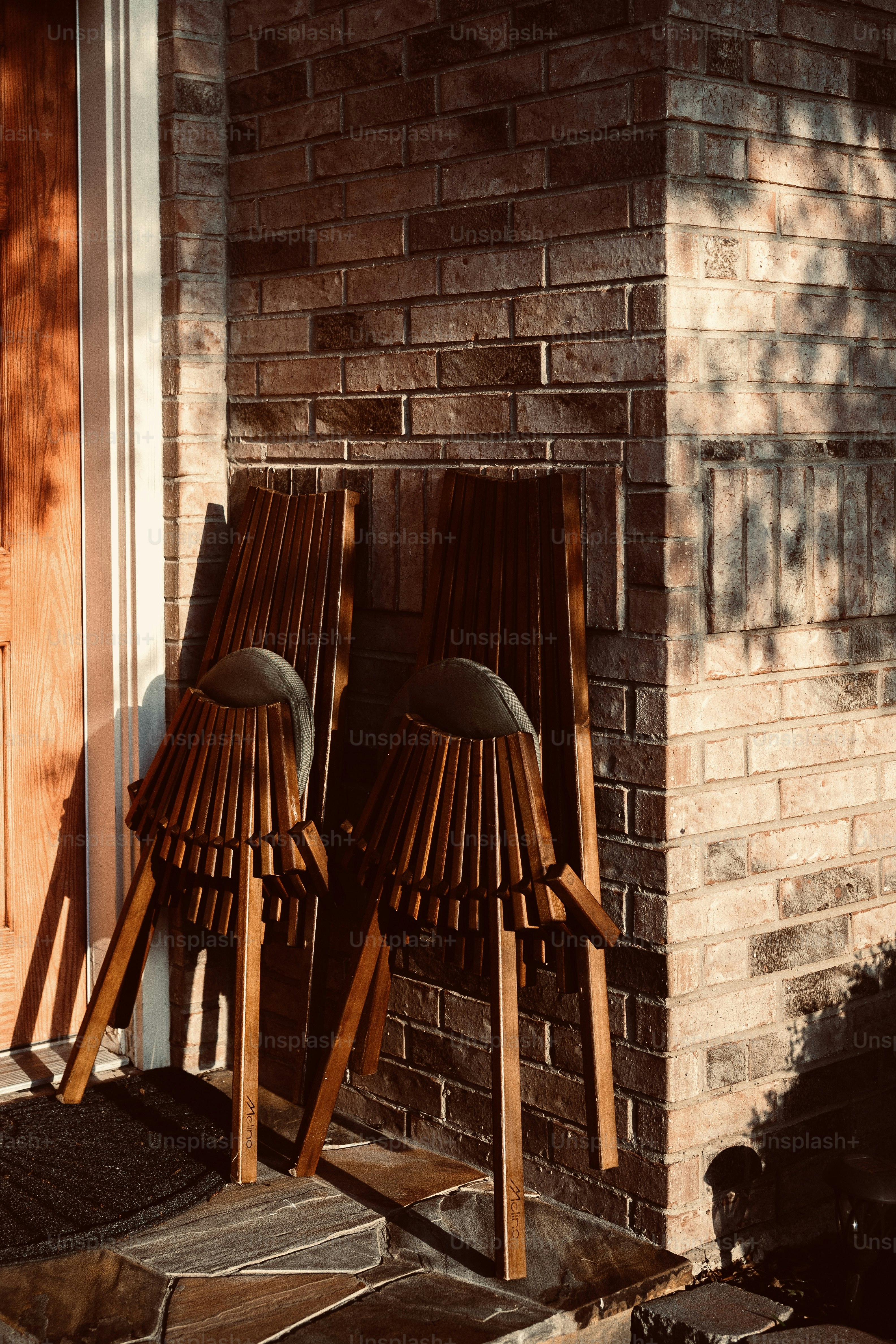 Two wooden chairs leaning against brick wall