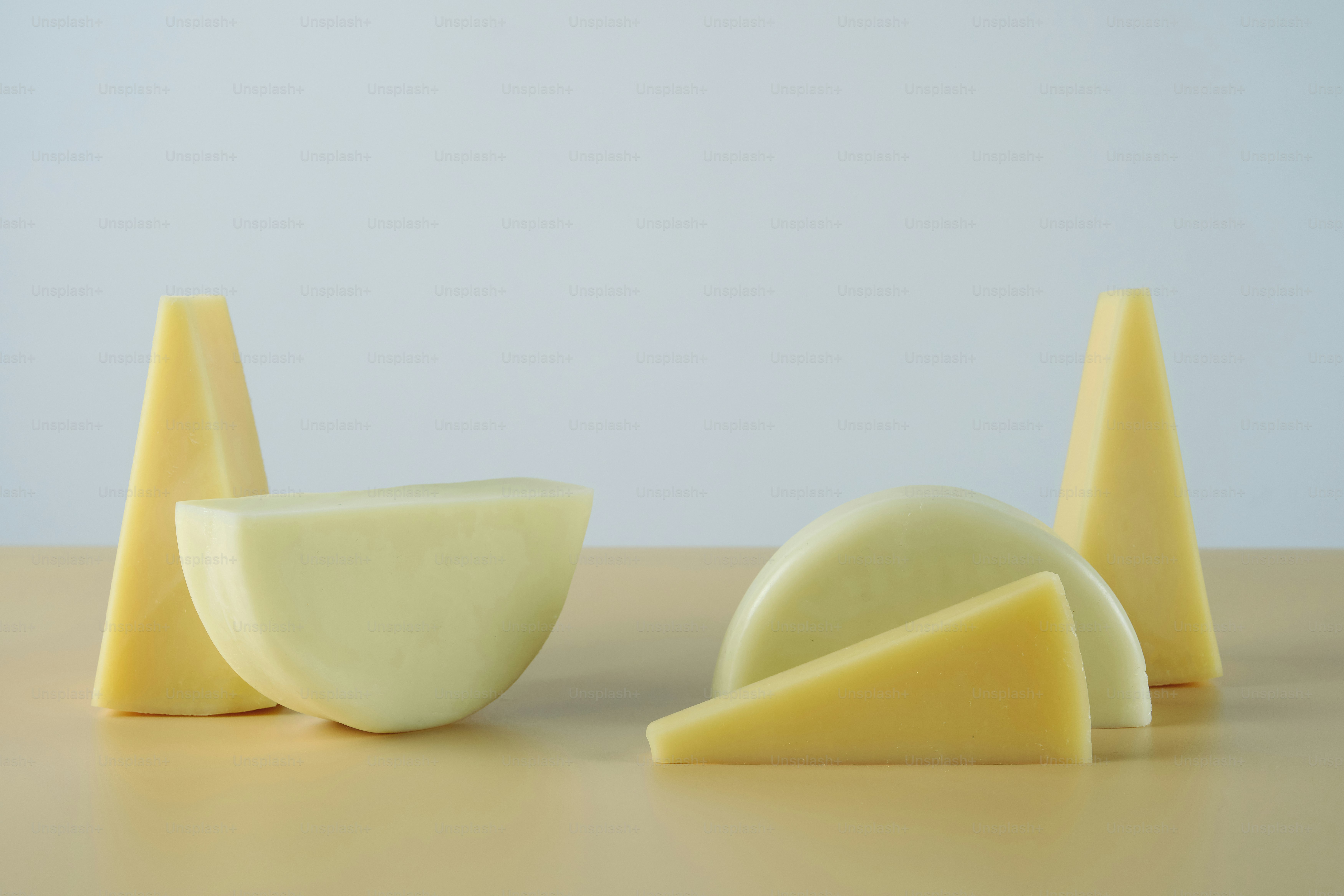 Verschiedene Käsestücke, die auf einer hellbraunen Oberfläche angeordnet sind.