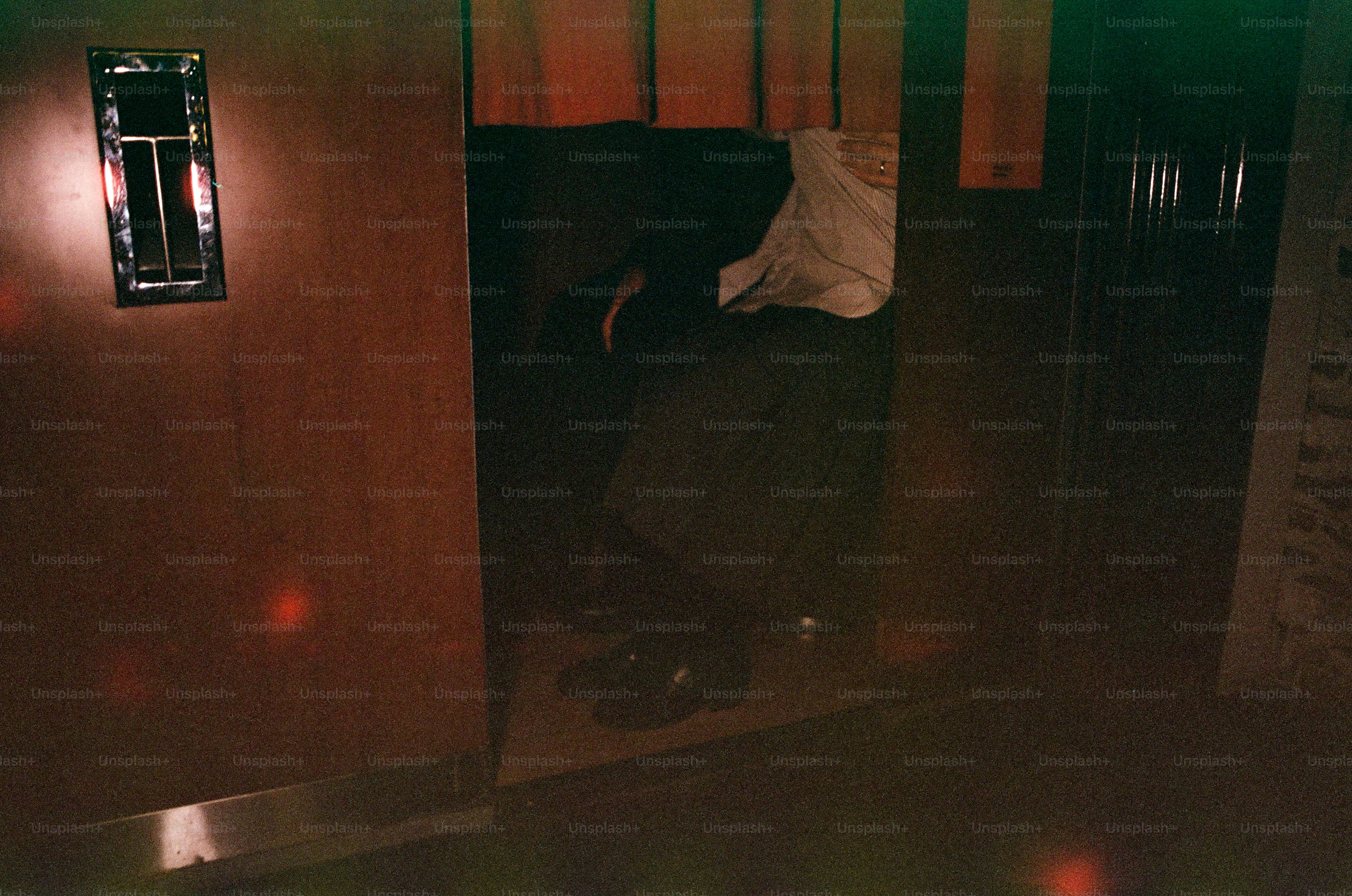 Person in a dark, enclosed space with red curtains.