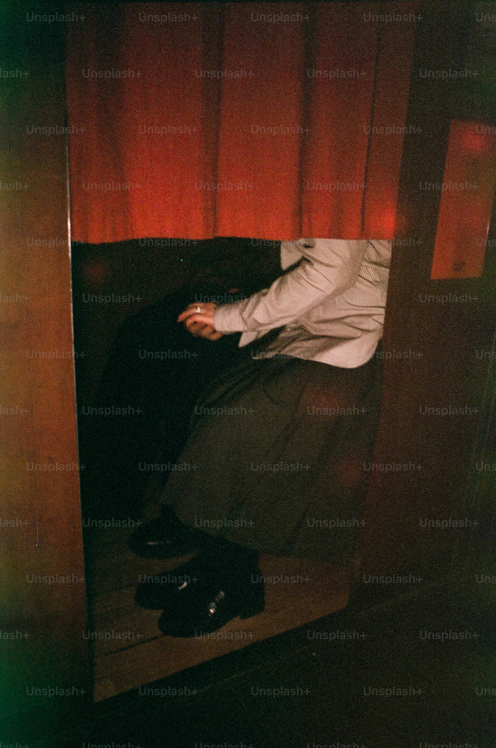 Person sitting in a booth with red curtain