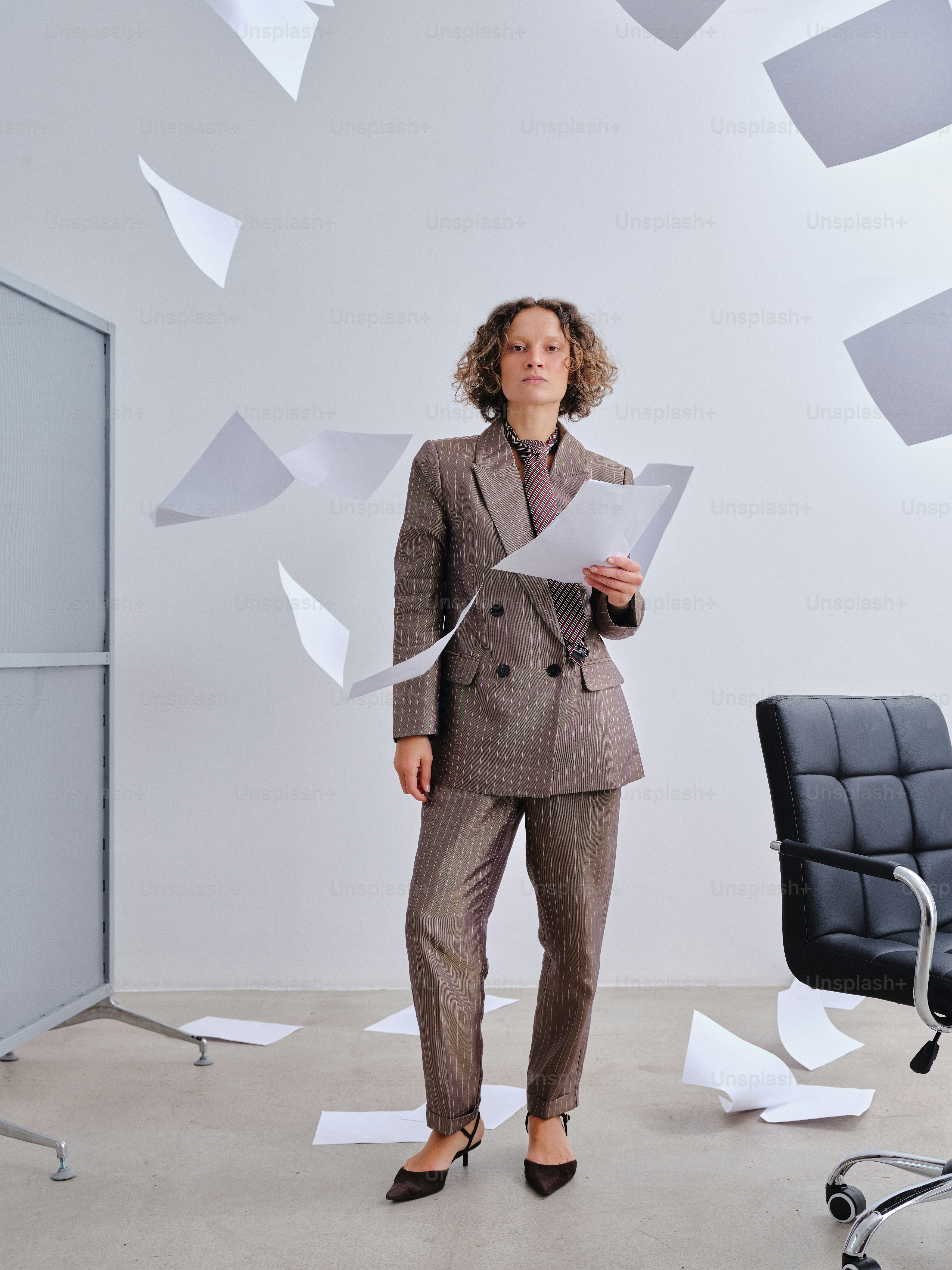 Frau im Anzug, umgeben von herabfallenden Papieren