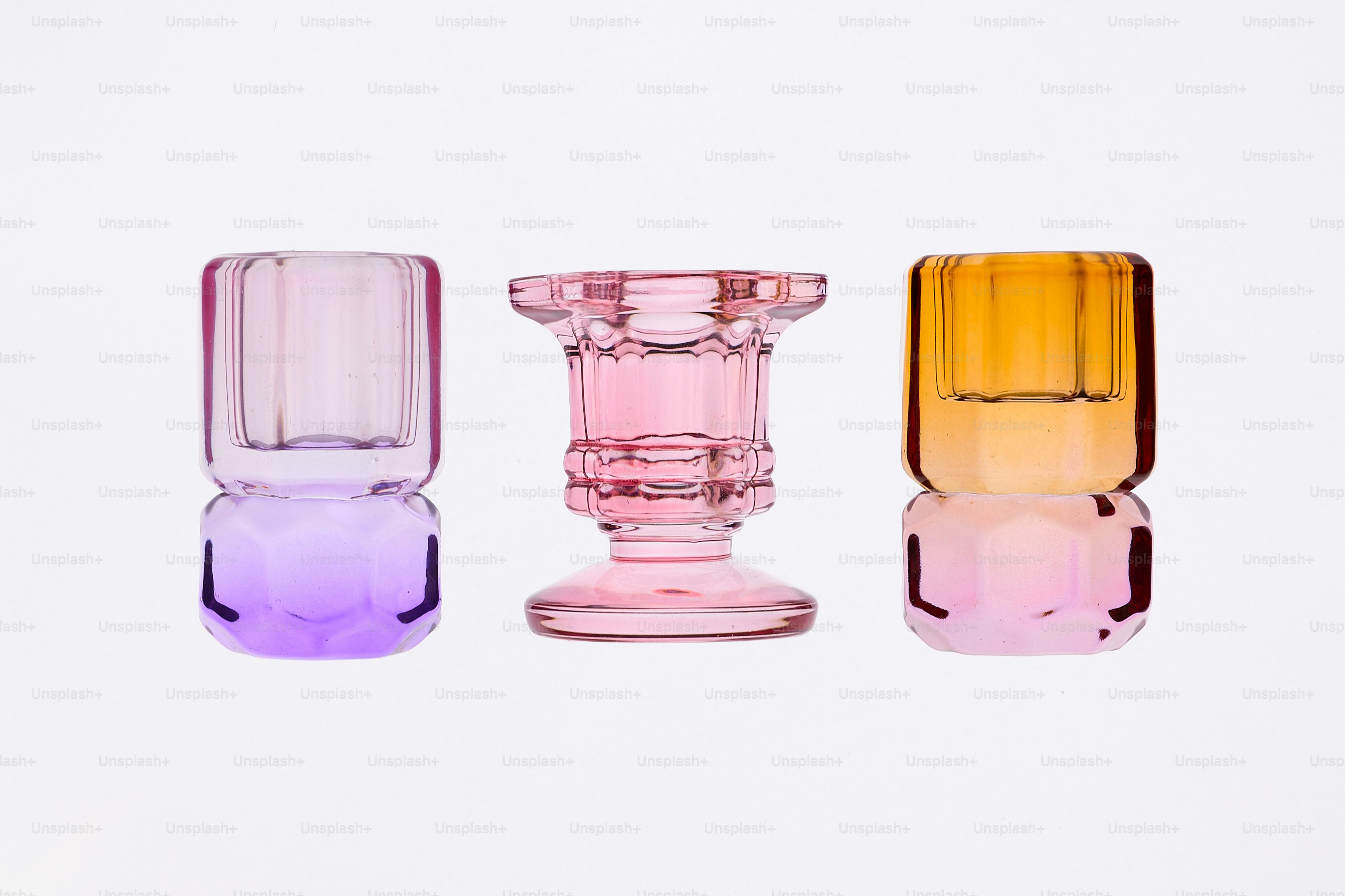 Trois bougeoirs en verre coloré sur fond blanc