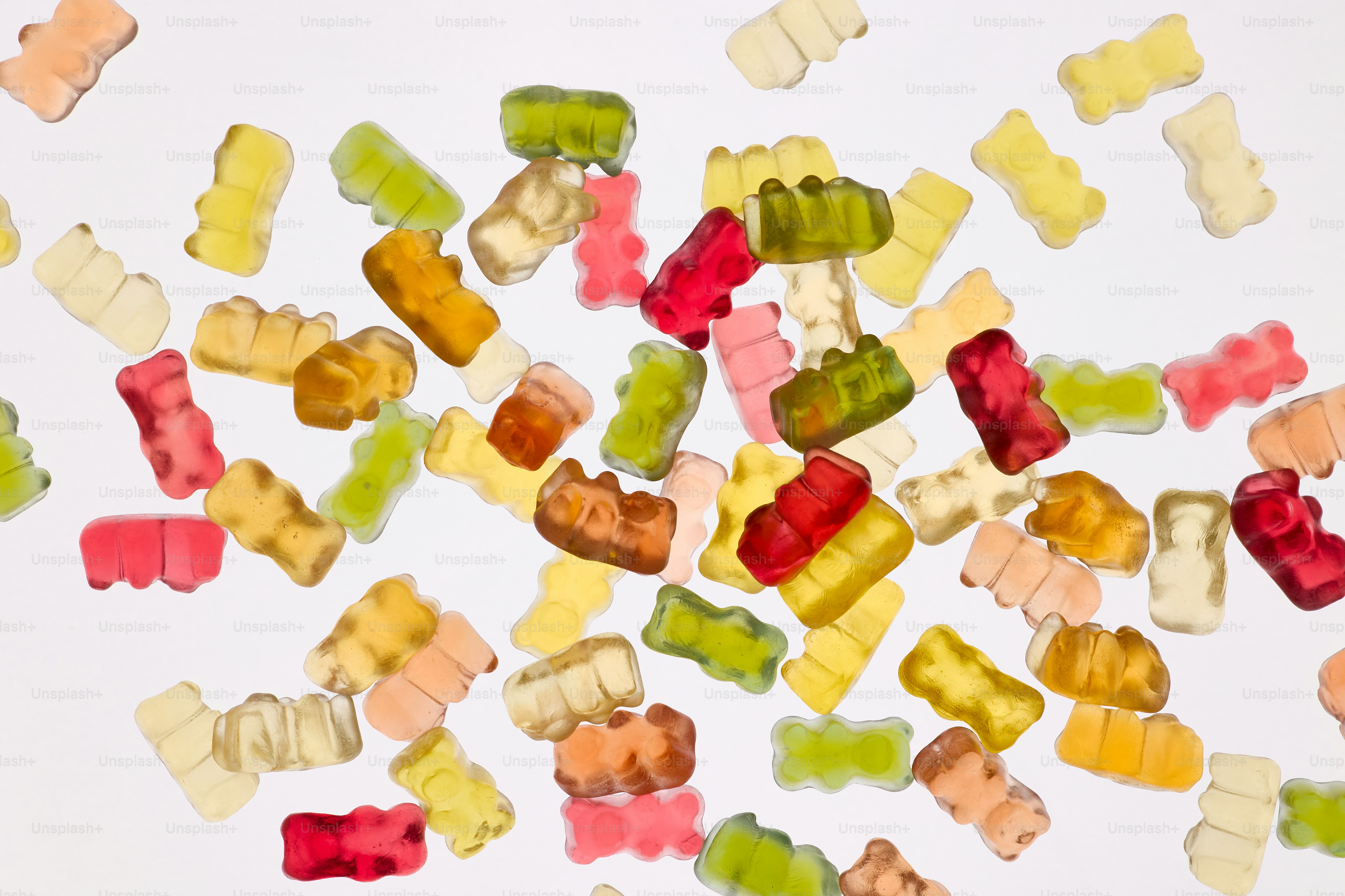 Oursons gommeux colorés dispersés sur un fond blanc