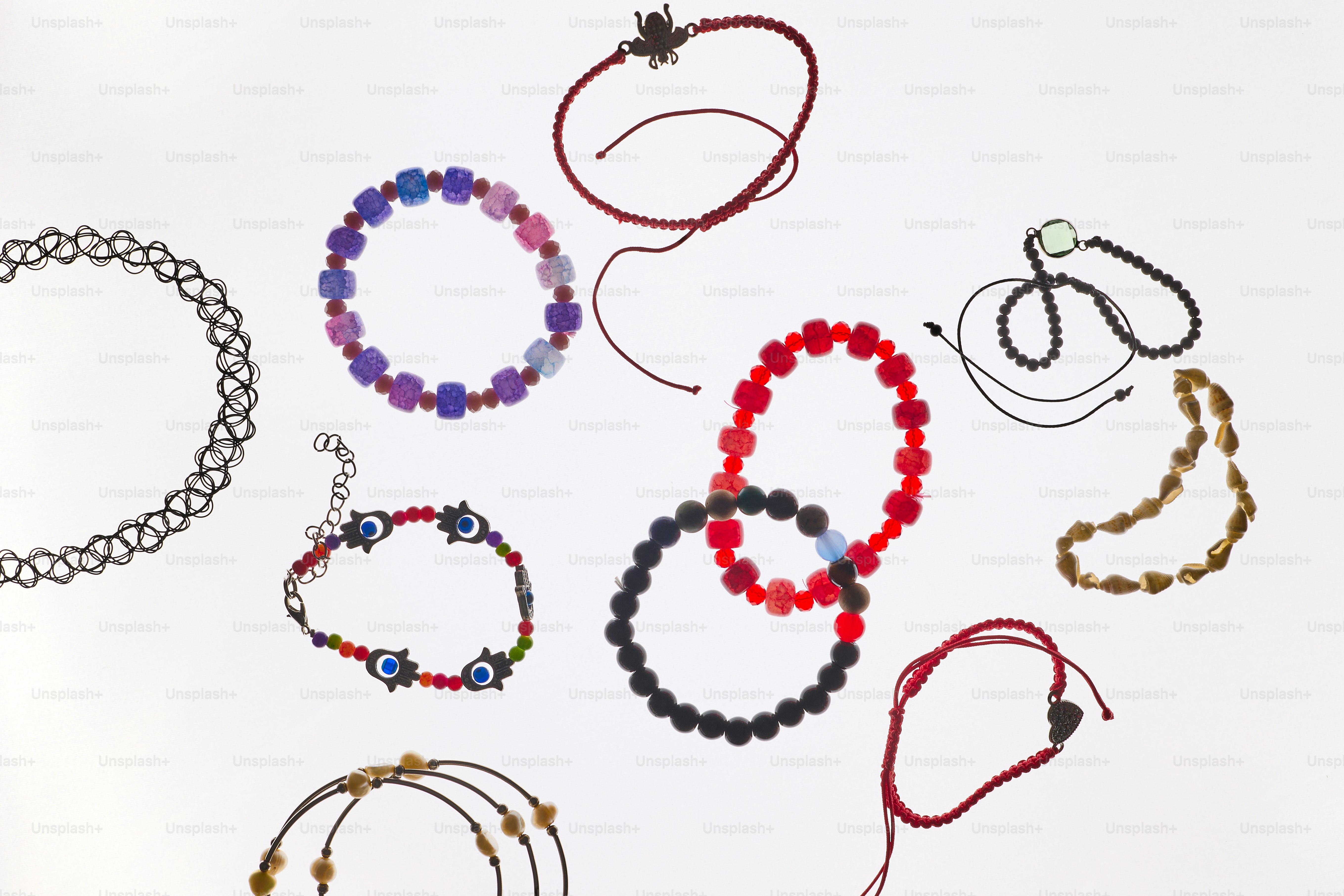 Divers bracelets et colliers colorés disposés sur fond blanc