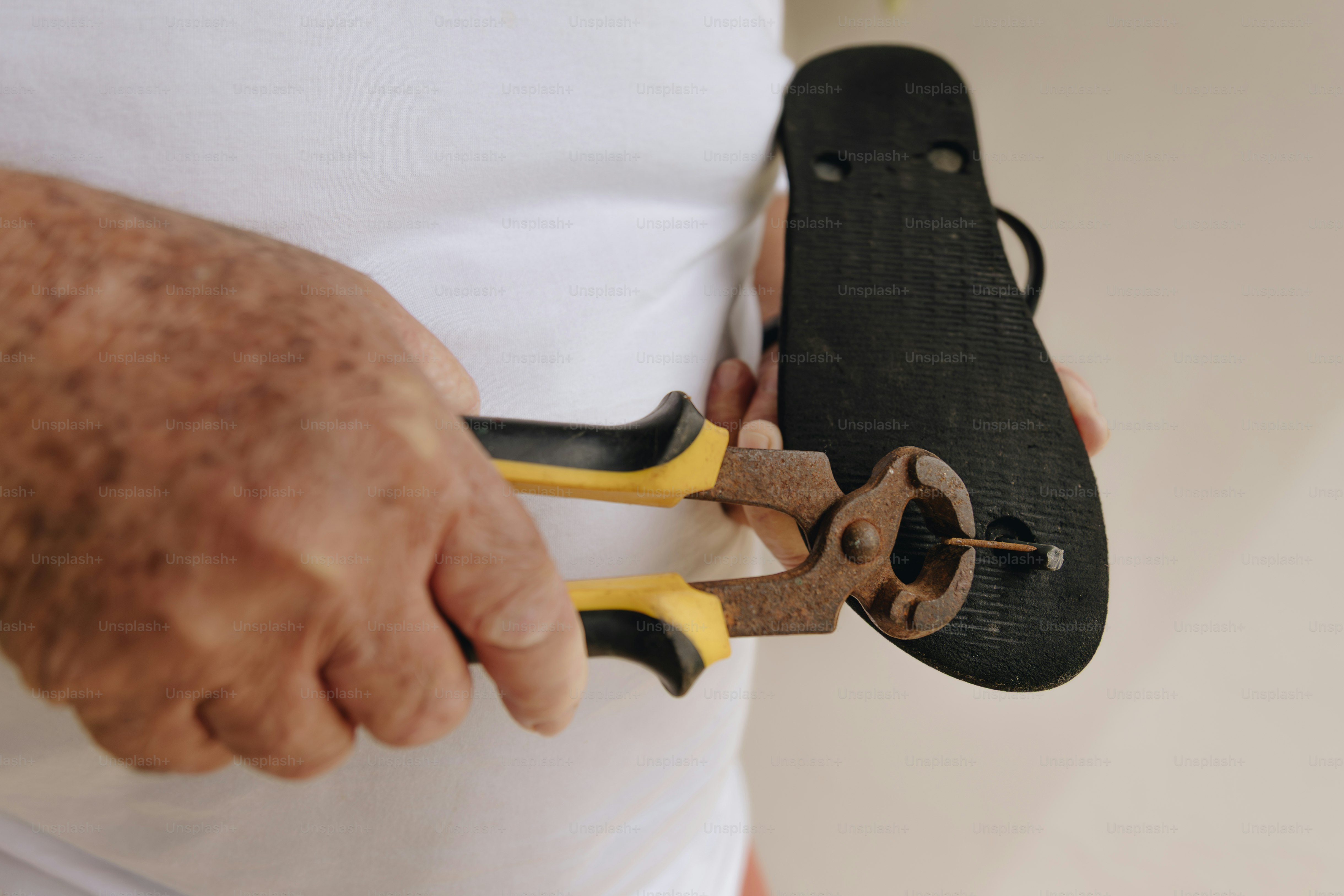 Mann entfernt Nagel von der Flip-Flop-Sohle mit einer Zange