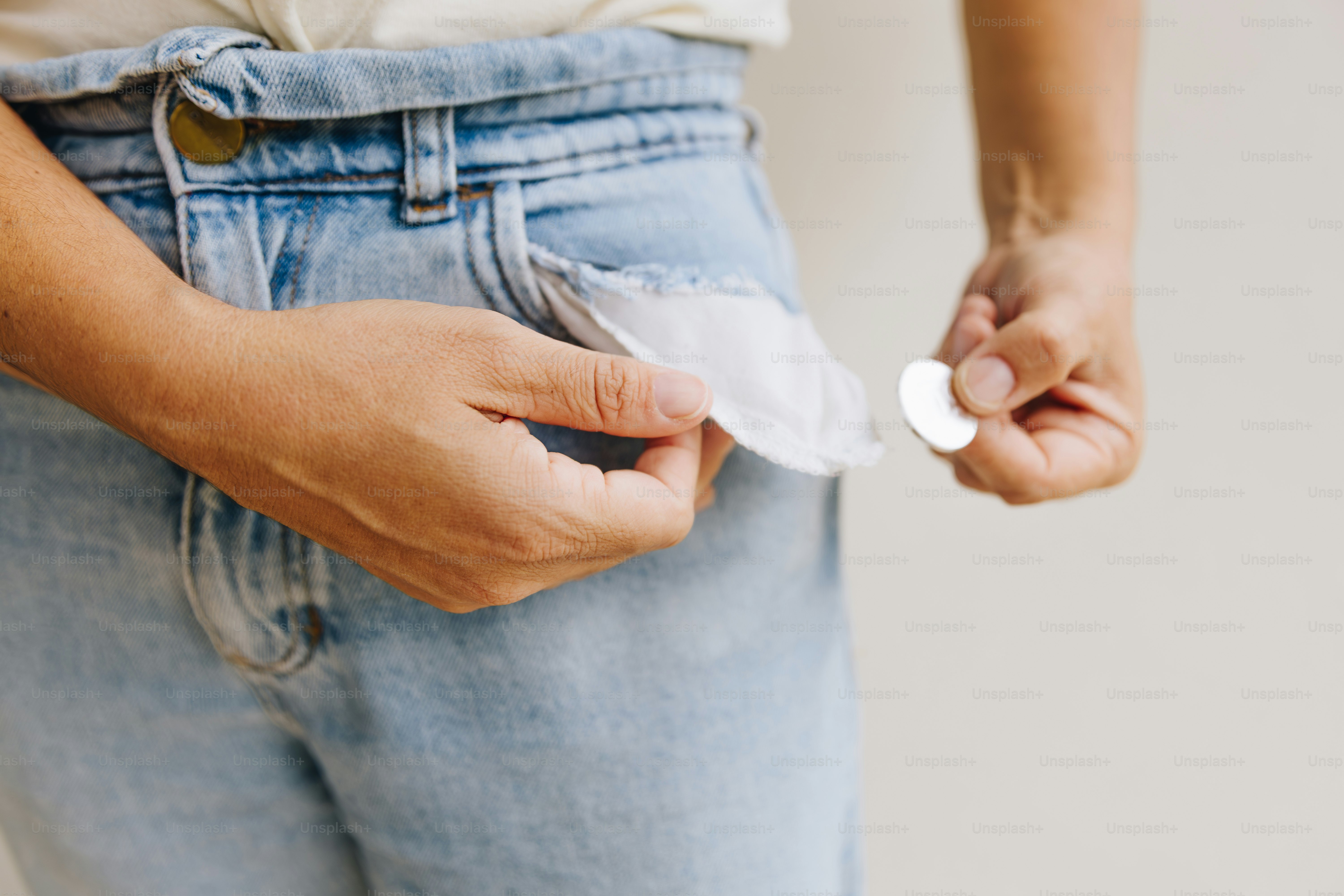 Person zeigt leere Taschen mit einer Münze