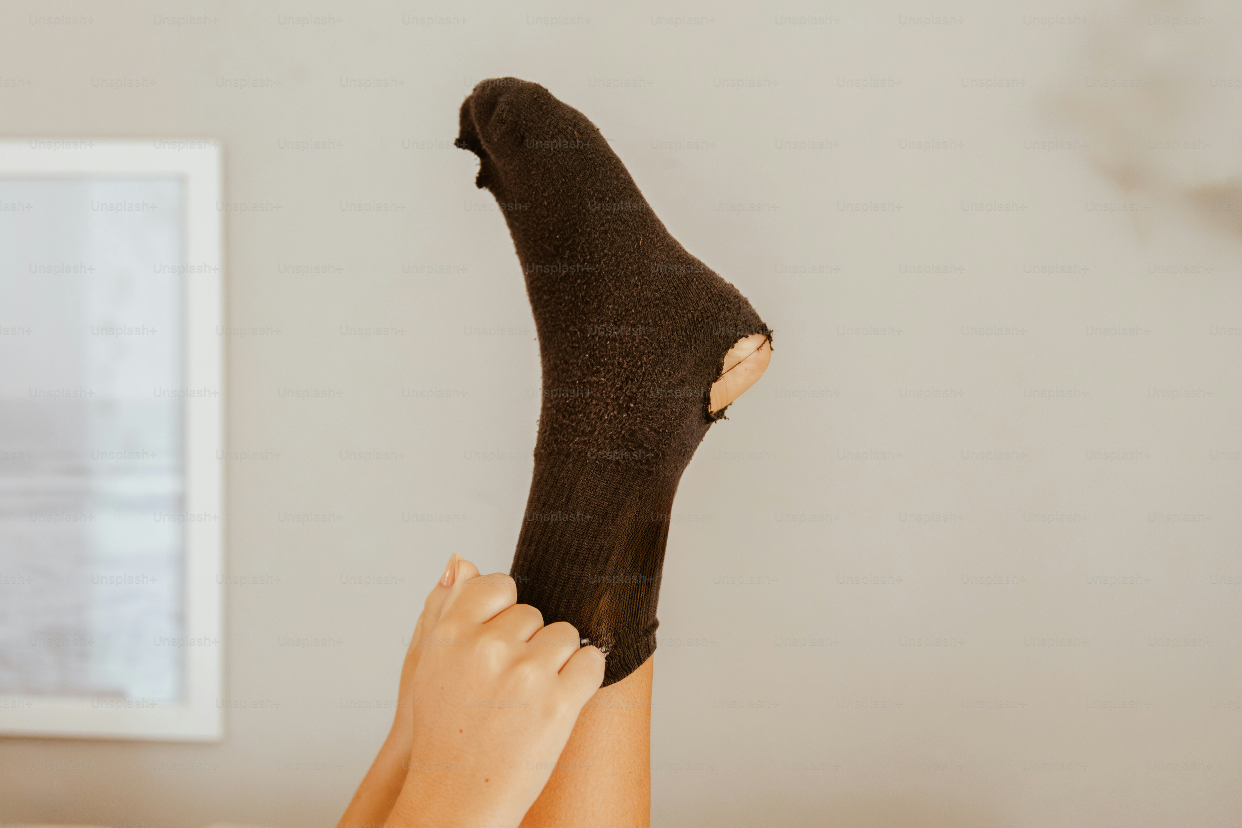 Das Bein einer Person trägt eine zerrissene braune Socke