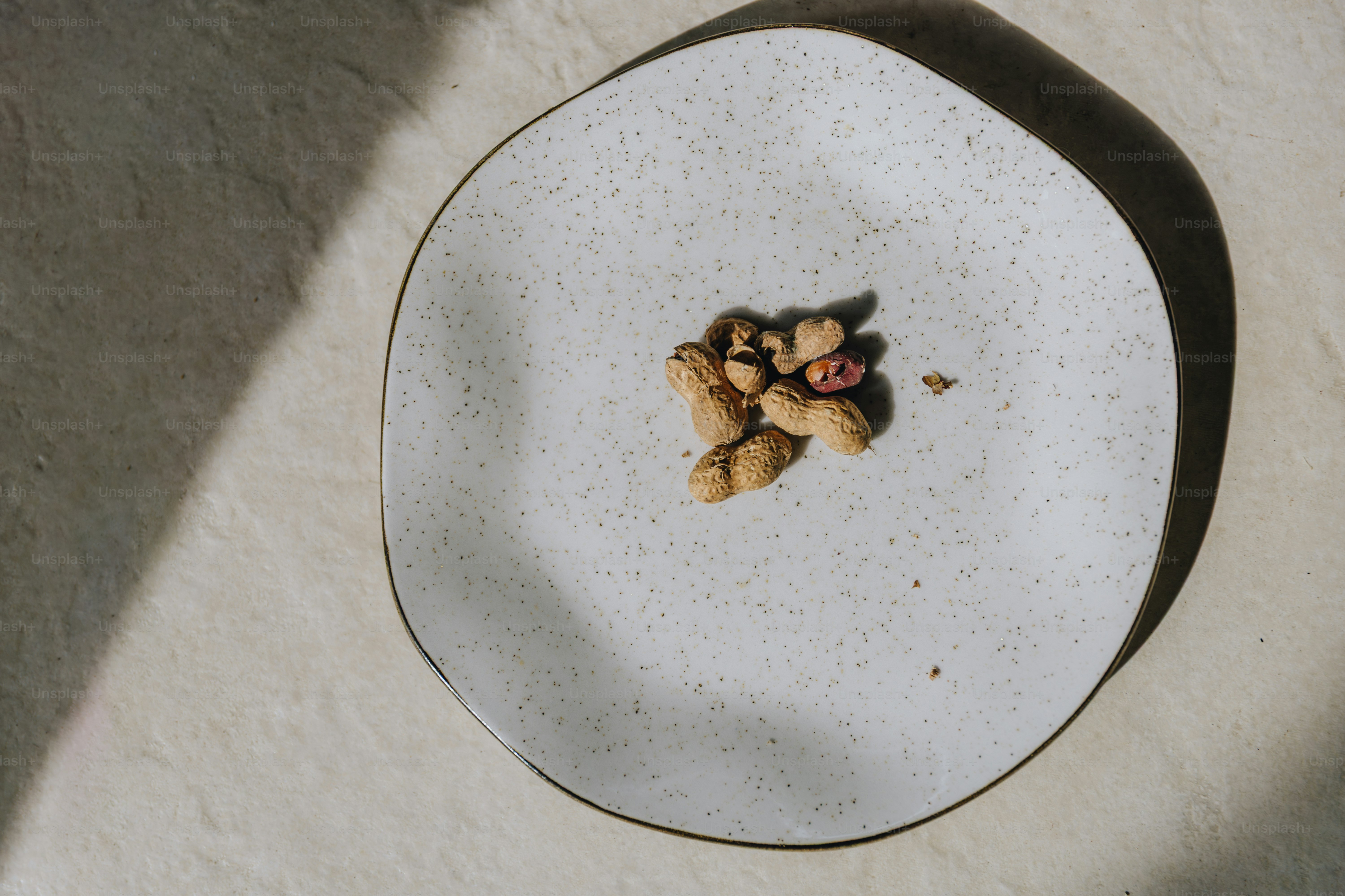 A small pile of peanuts on a speckled plate.