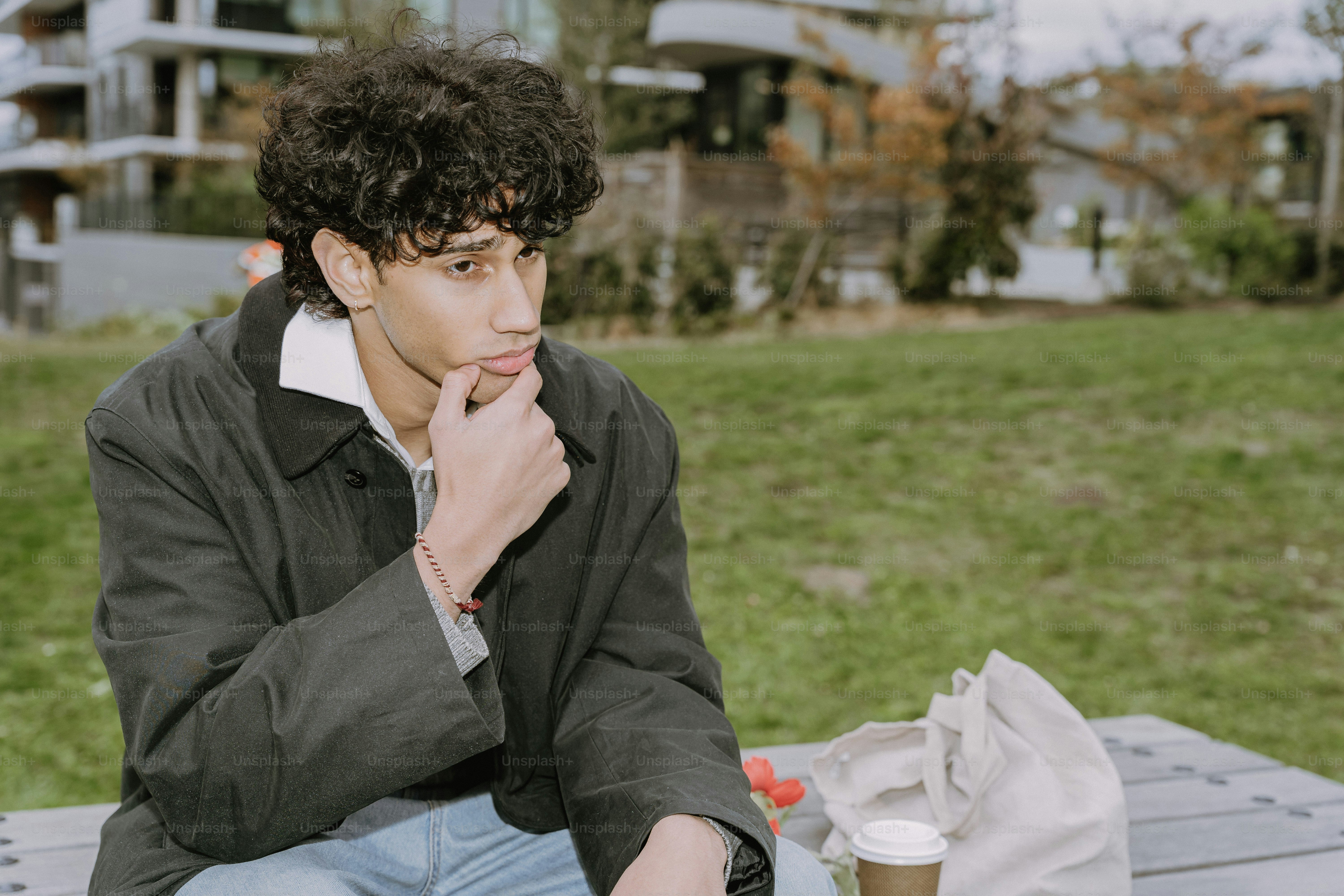 Young man sitting outdoors with a thoughtful expression.