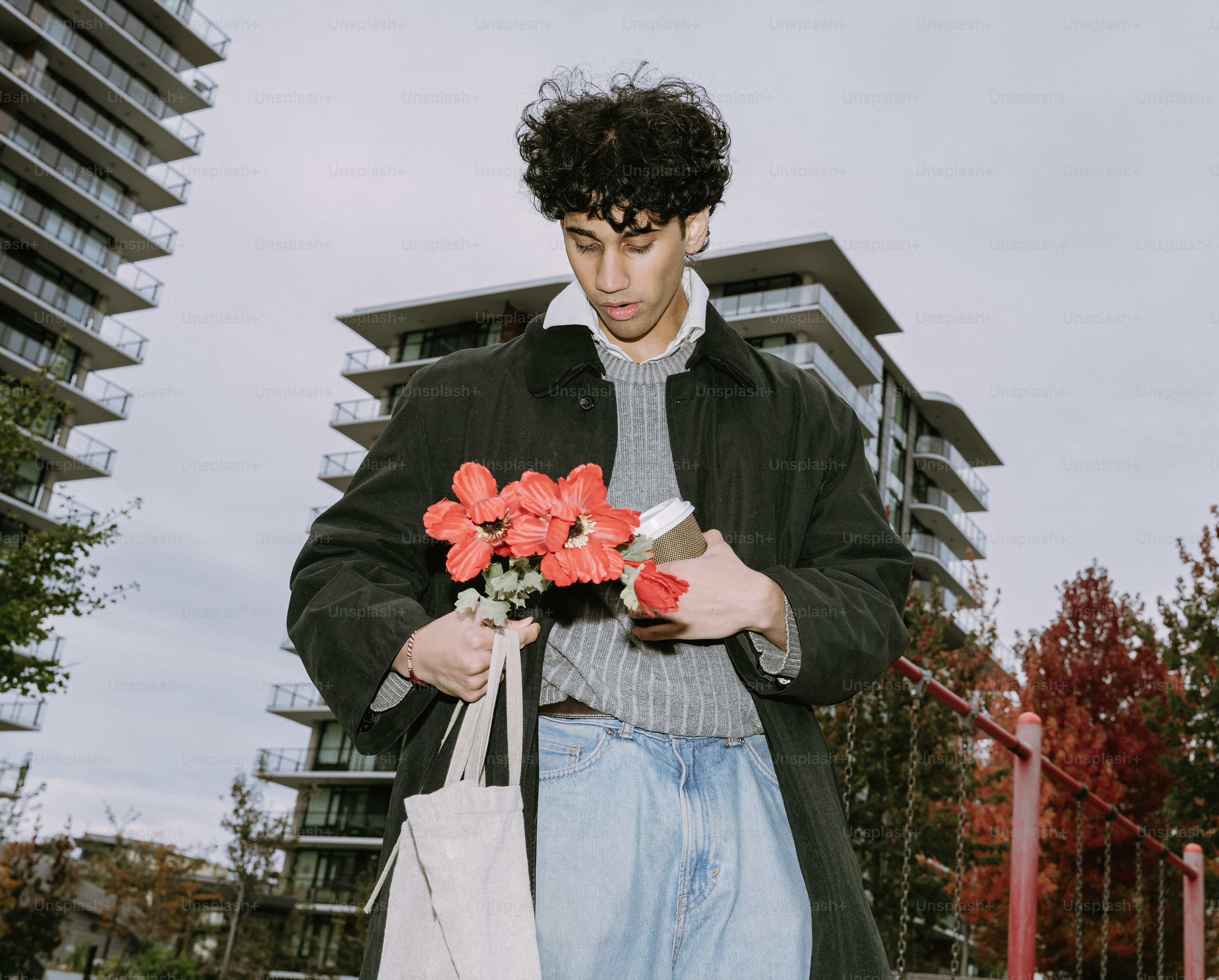Man holding flowers and coffee near buildings