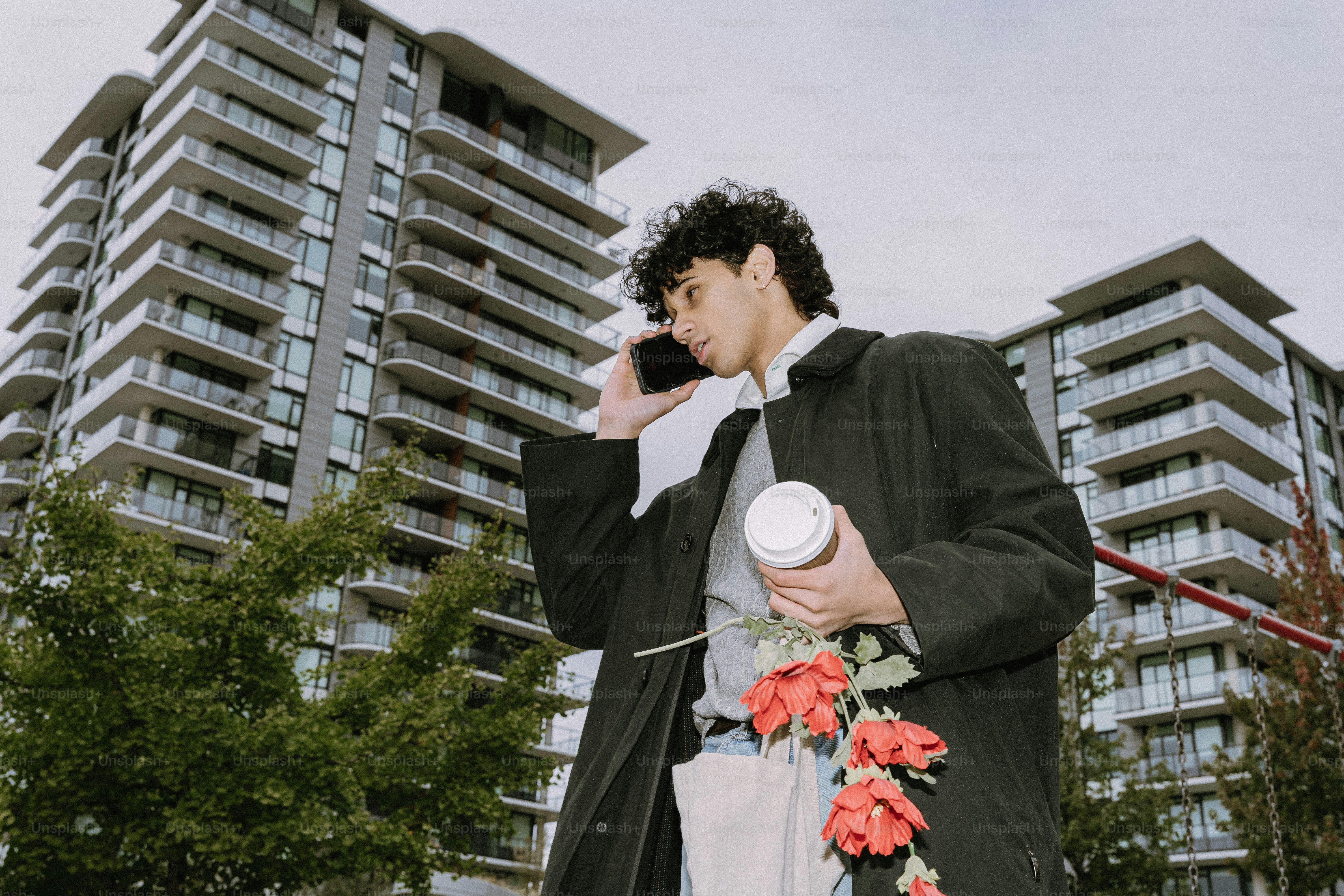 Man with flowers and coffee on phone.