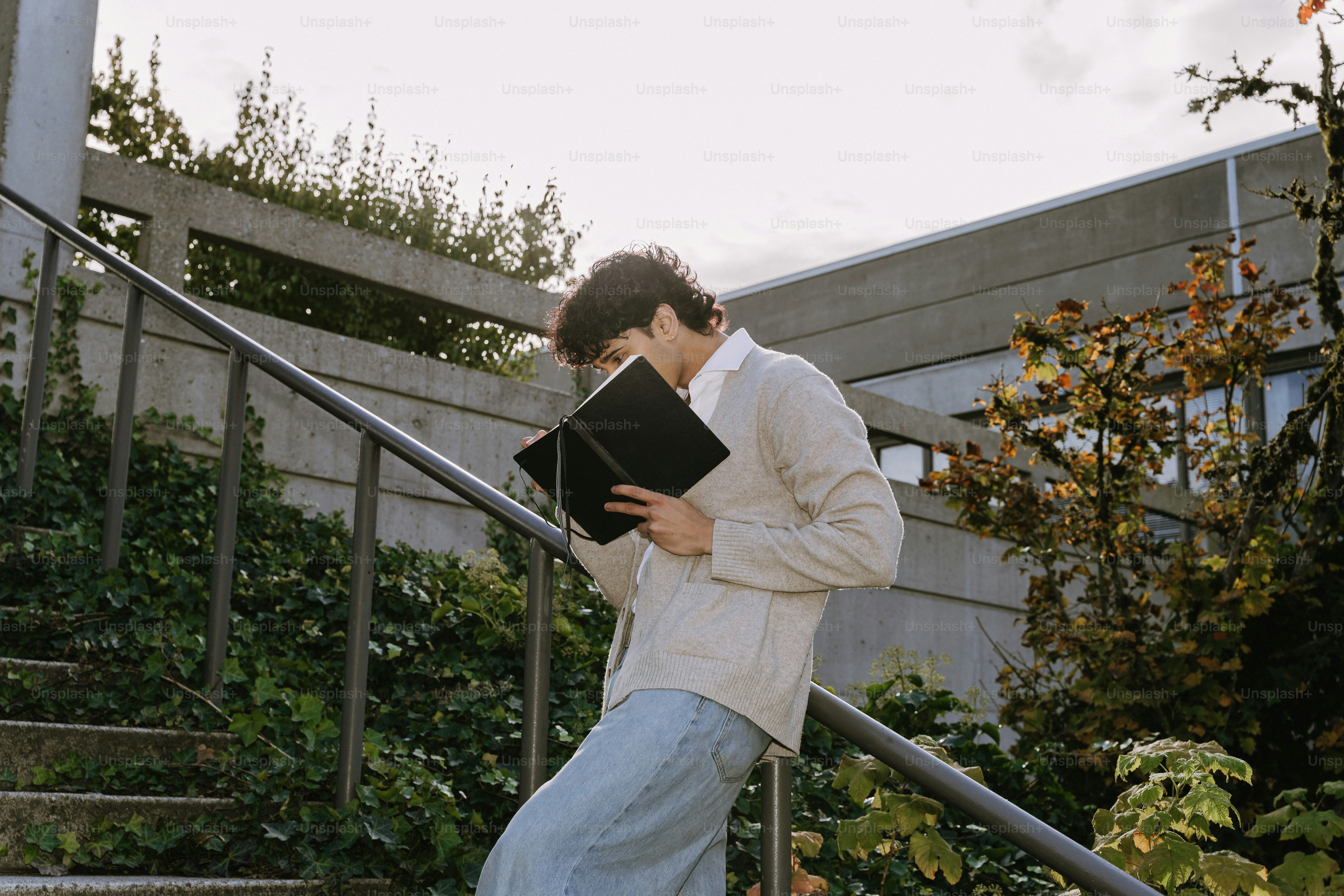 Young man reading a book on outdoor stairs.