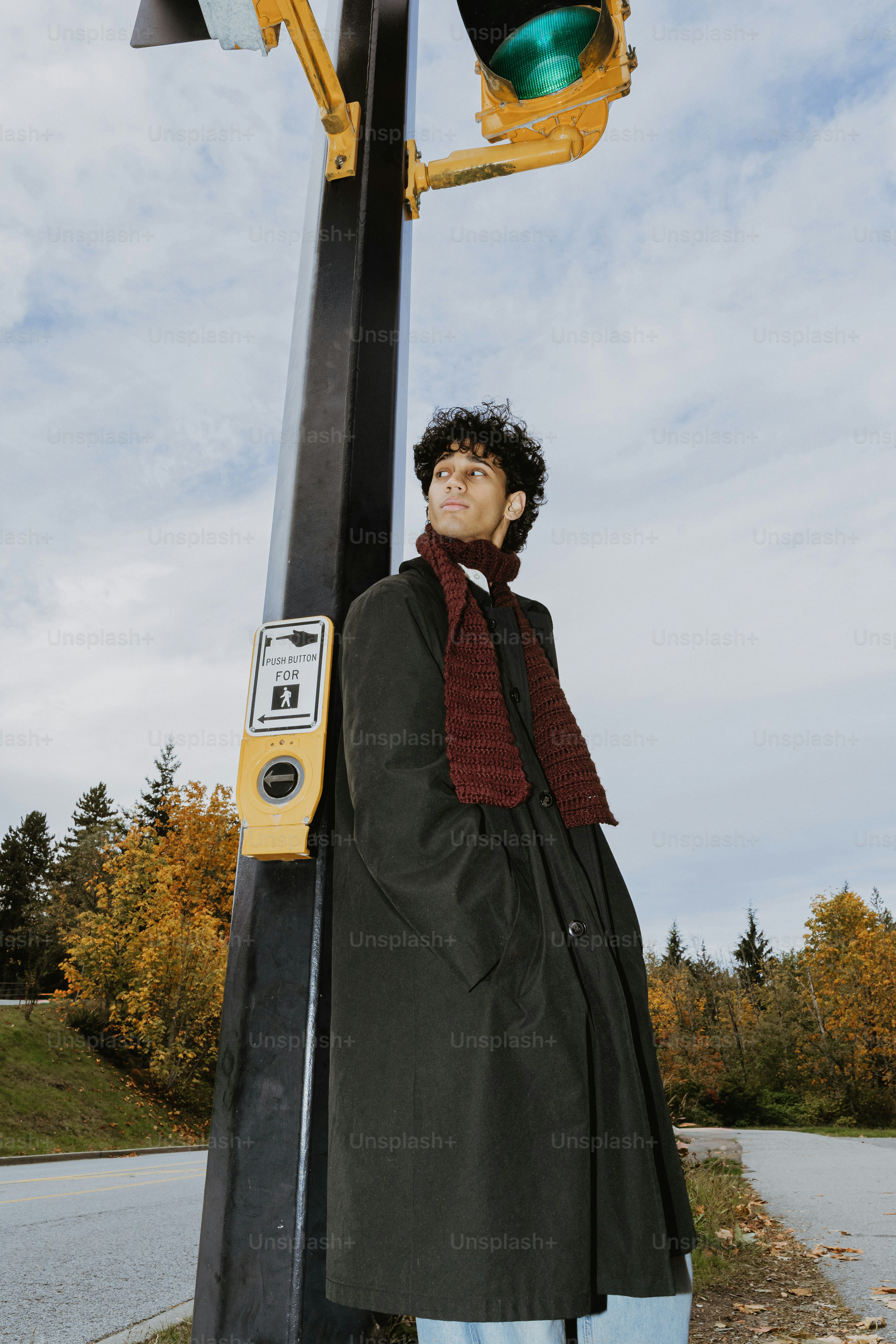 Man in coat and scarf near traffic light