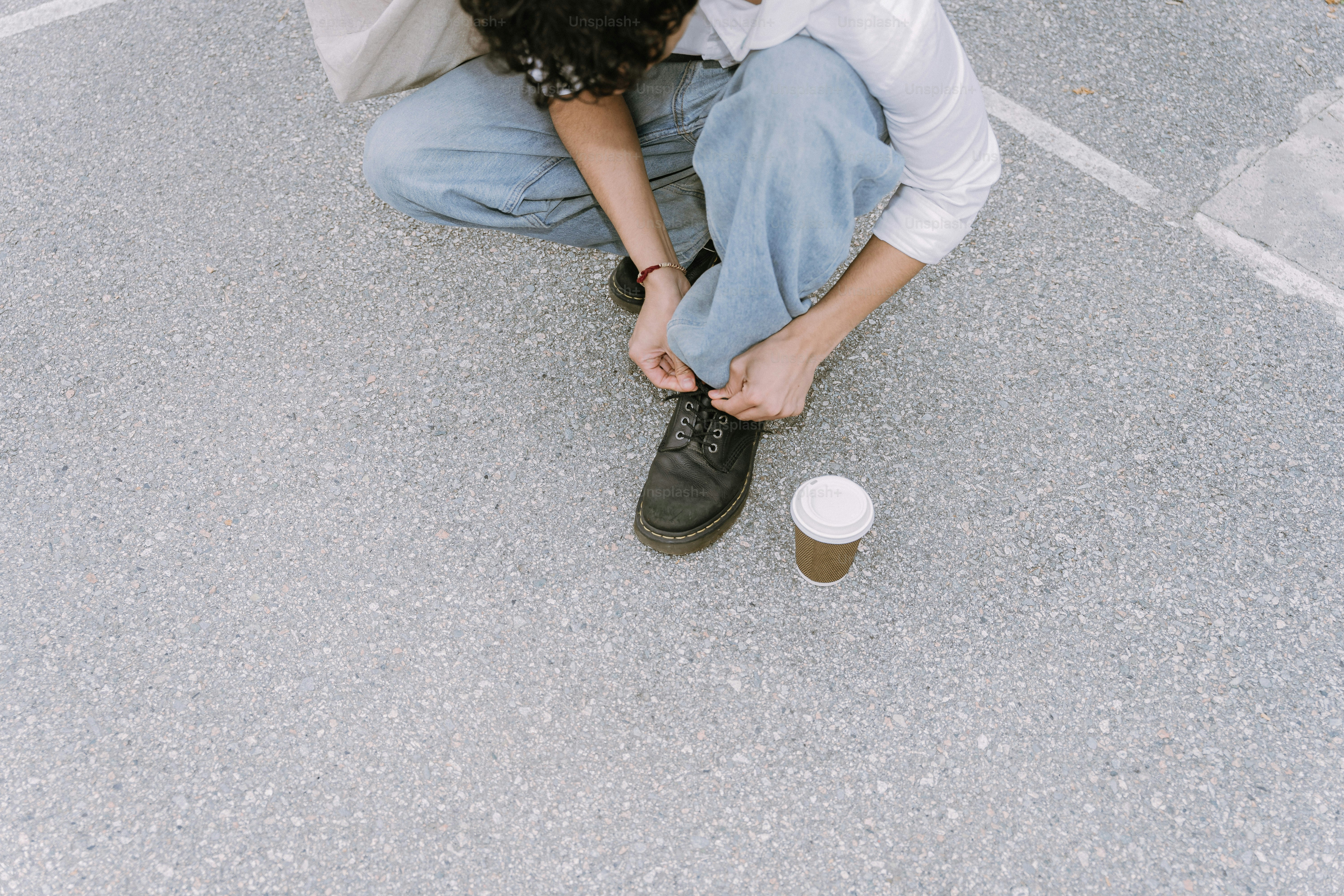 Person tying shoelaces next to coffee cup.