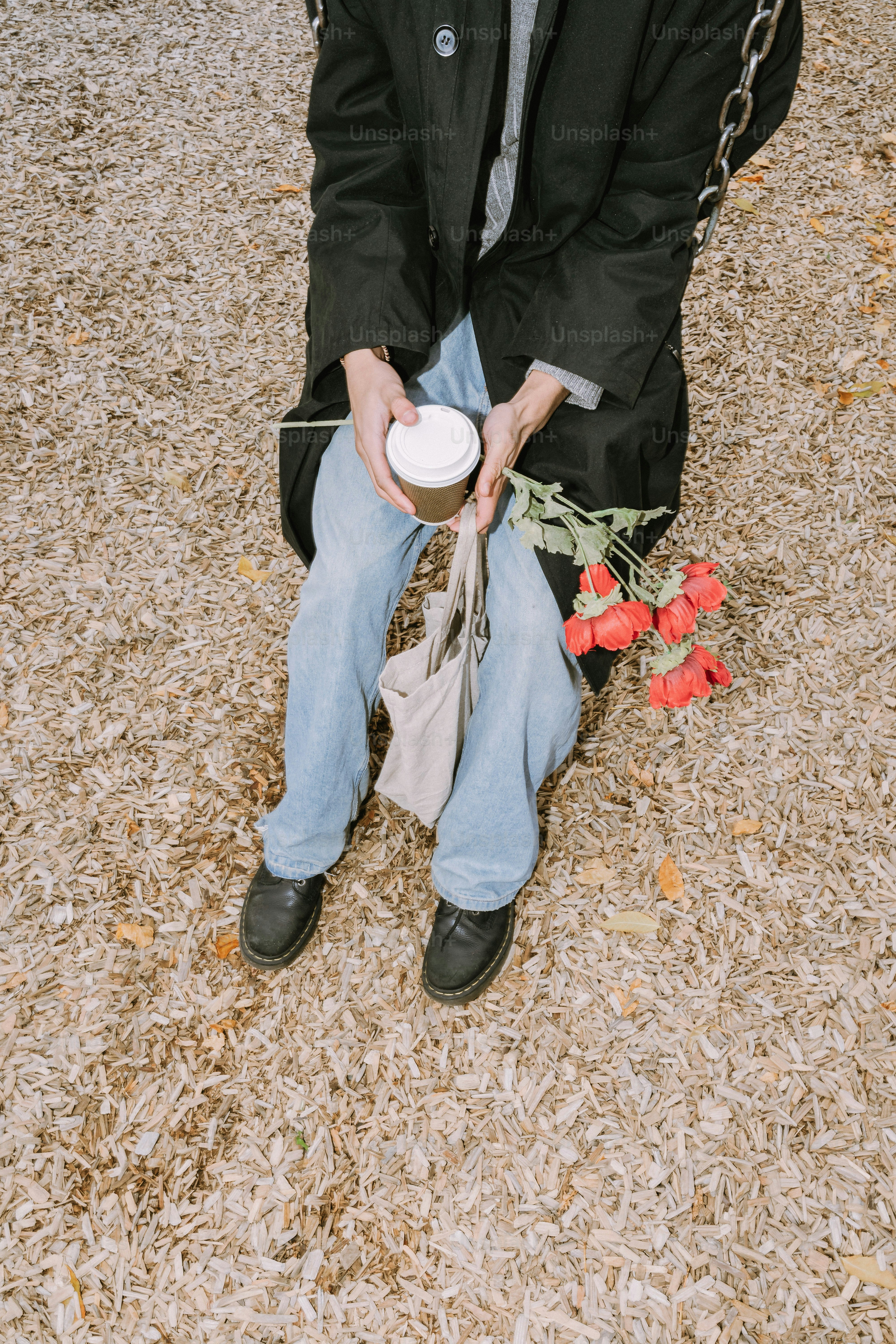 Person with coffee and roses on a swing