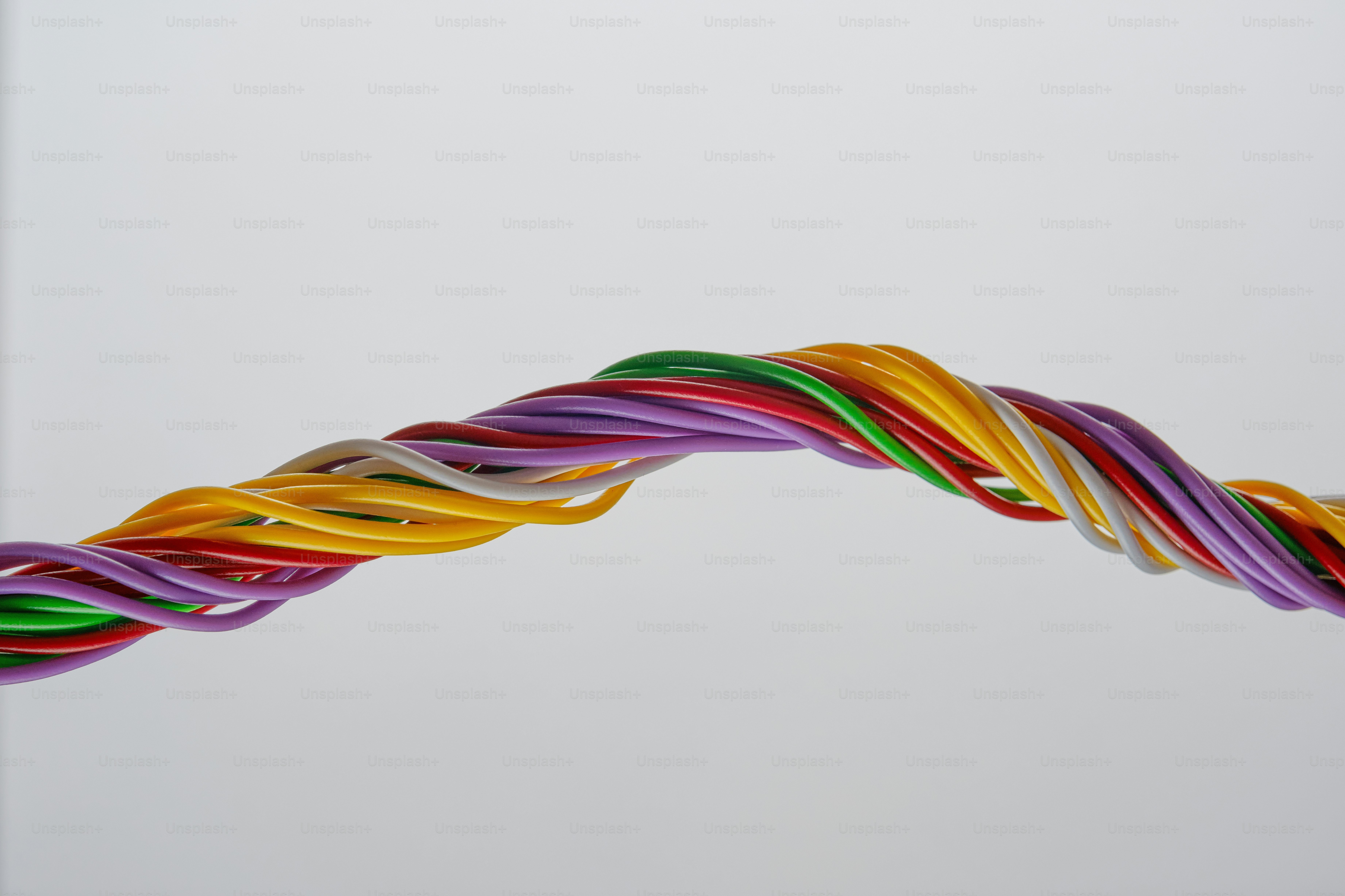 Ein verdrehtes Bündel bunter Drähte vor weißem Hintergrund