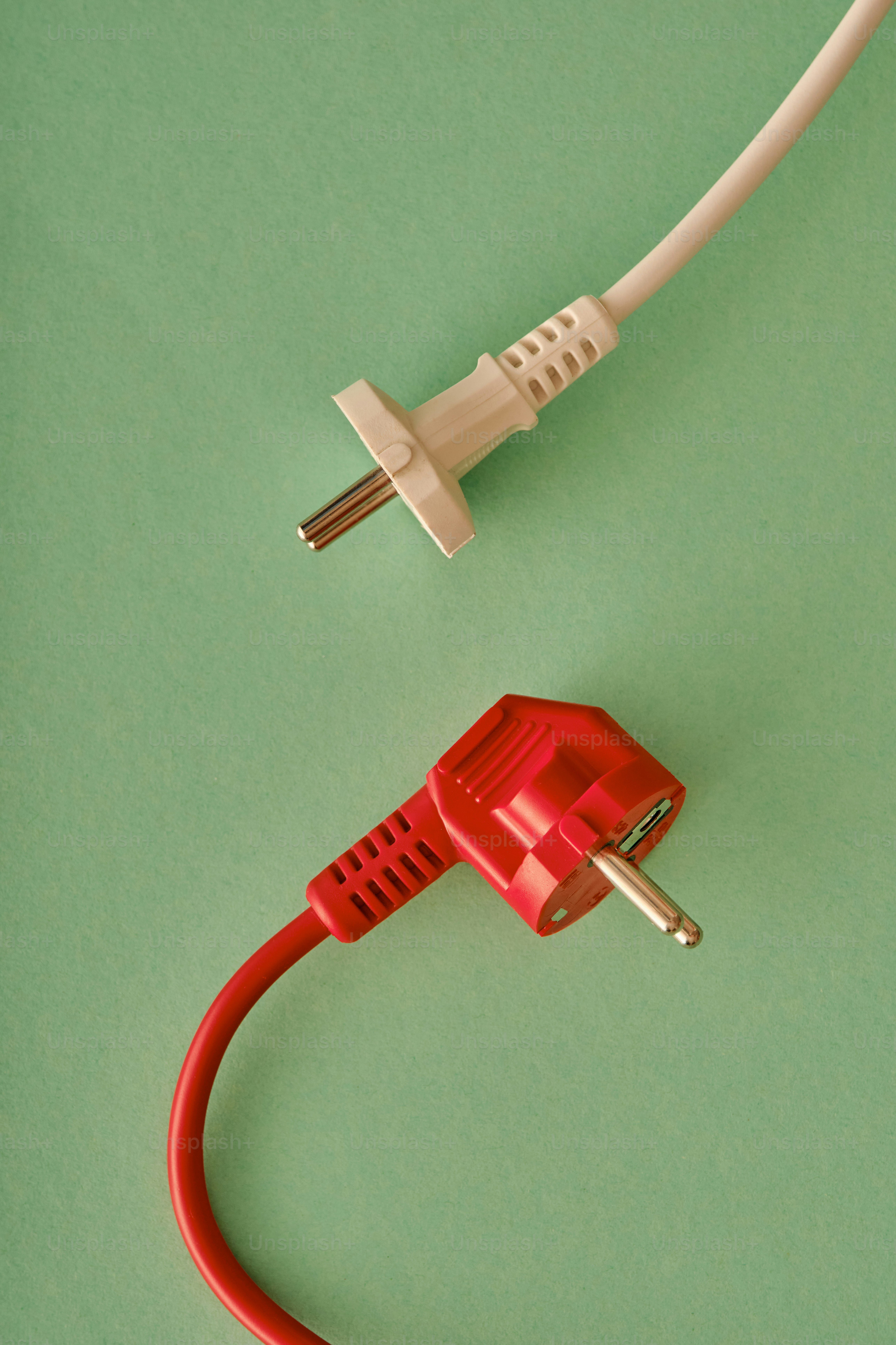Two electrical plugs on a pastel background