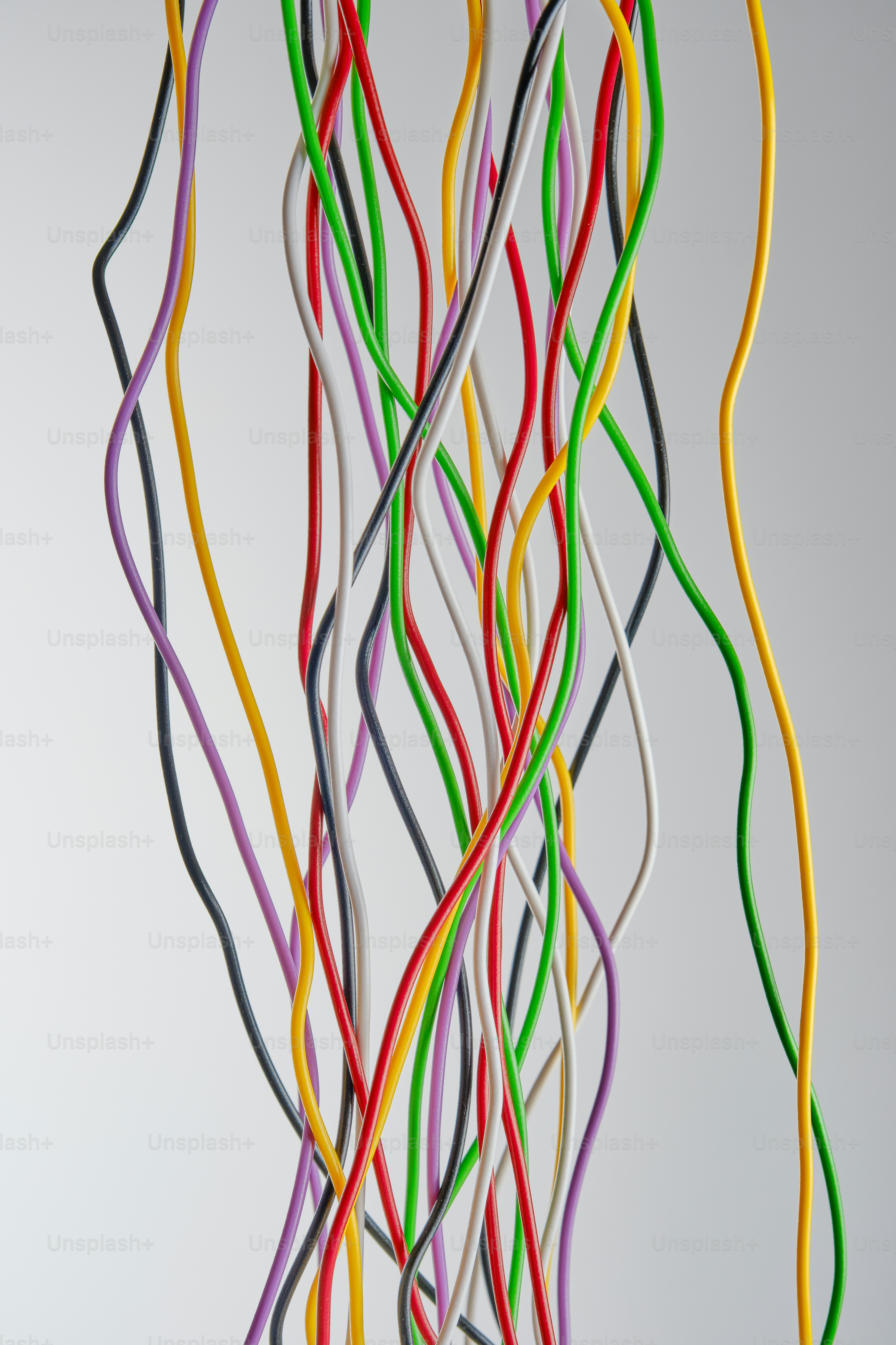 Bunte elektrische Drähte, die sich vor einem grauen Hintergrund verheddern